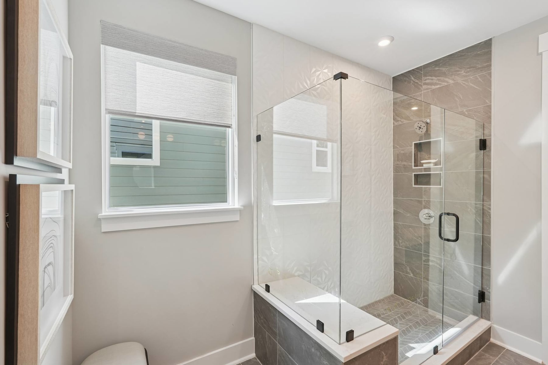 A modern, minimalist bathroom with a glass-enclosed shower, a white vanity, and a small window providing natural light.