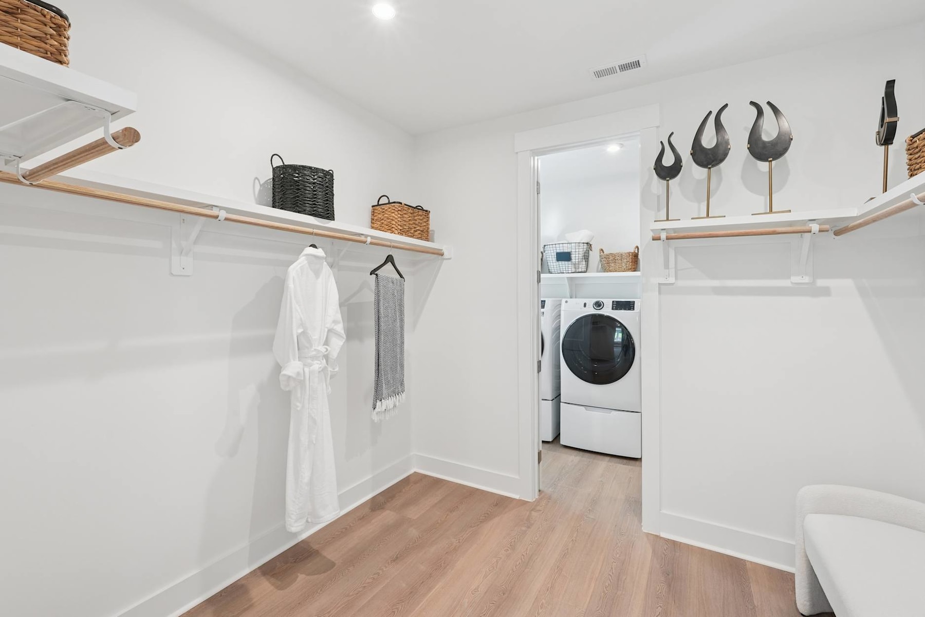 A bright and spacious laundry room with wooden shelves, a washing machine, and decorative wall accents.