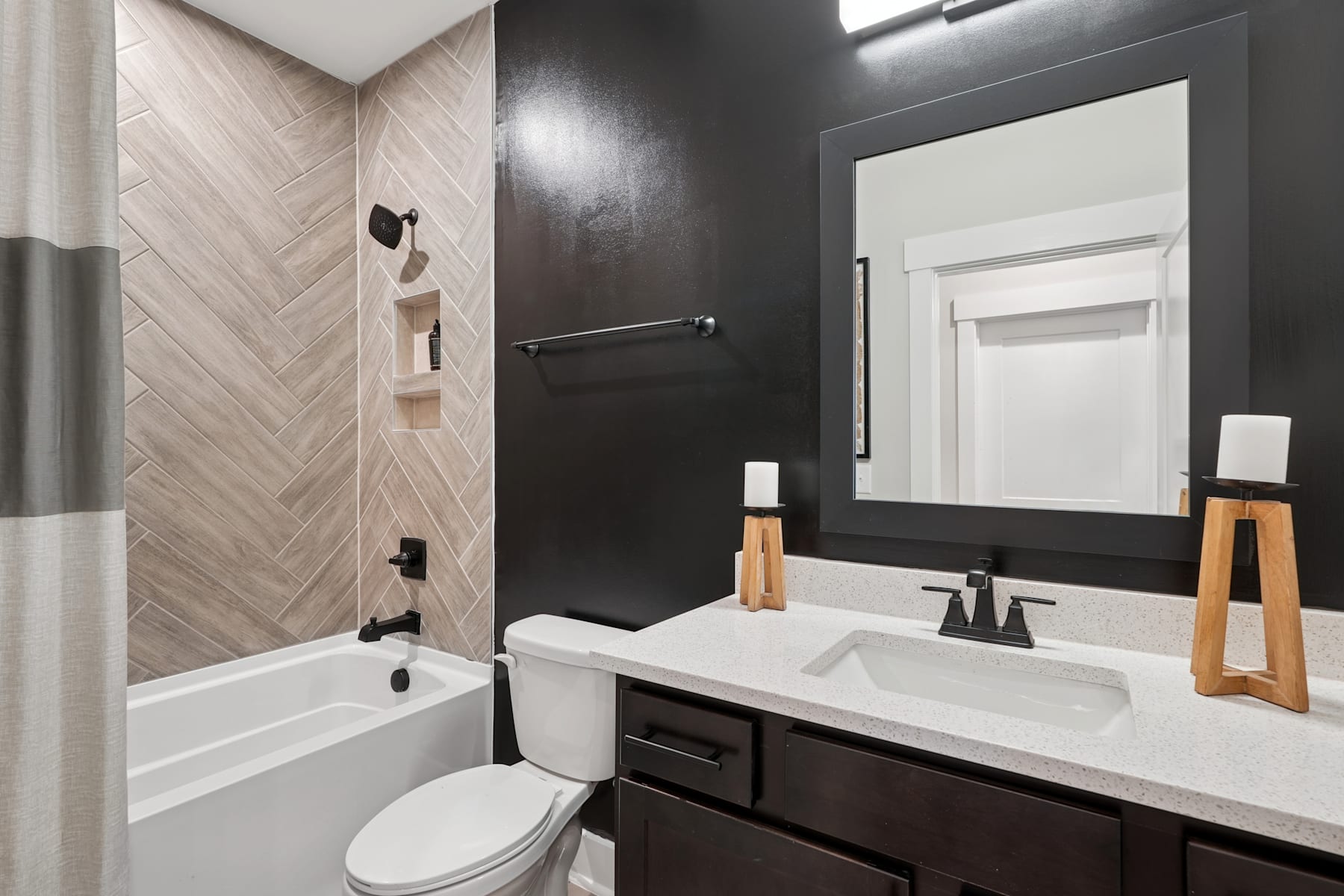 A modern bathroom with a white vanity, a large mirror, and a tiled wall pattern, creating a sleek and stylish interior design.