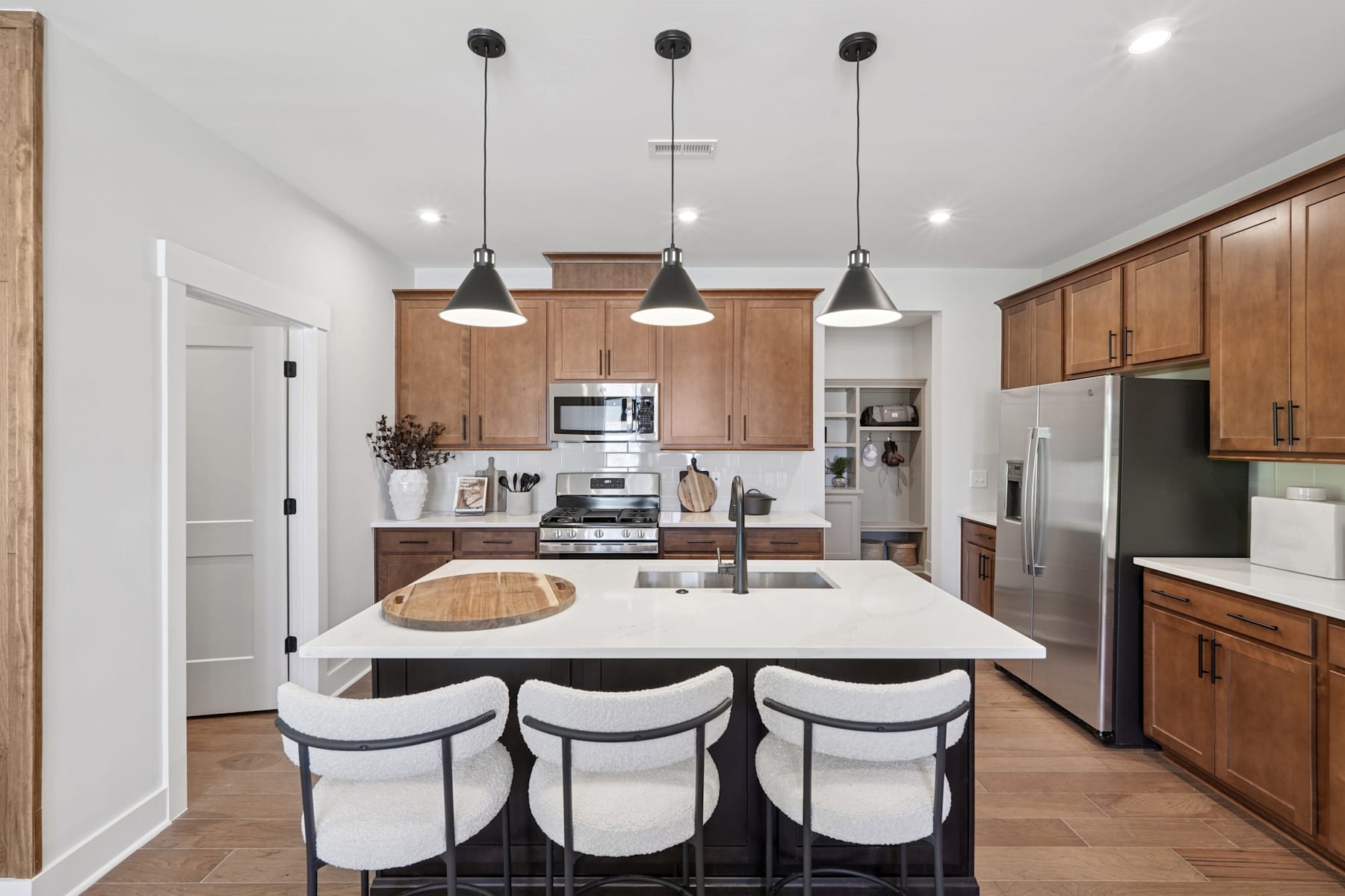 A modern and spacious kitchen with wooden cabinets, a large white countertop, and three pendant lights hanging above the island.