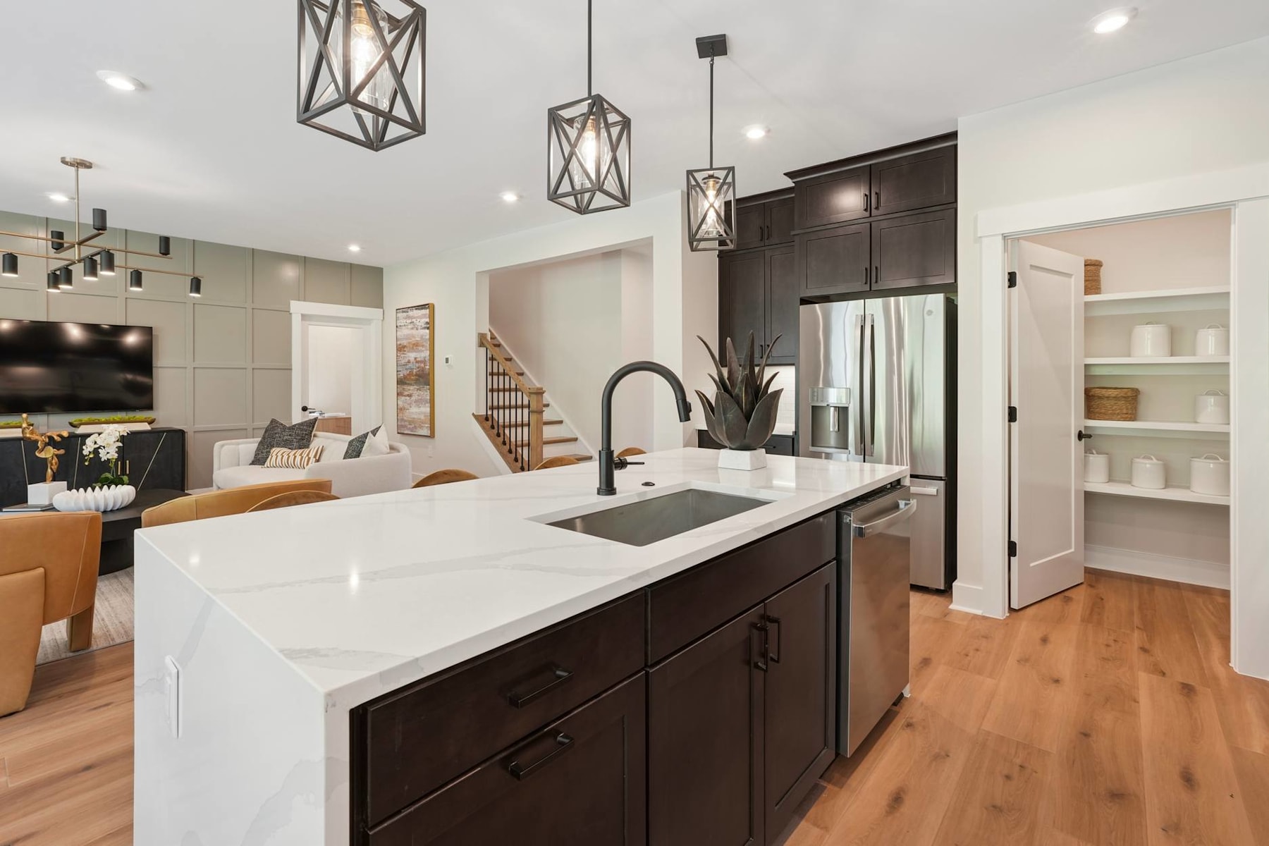 A modern and stylish kitchen with dark wood cabinets, a large white countertop, and pendant lighting fixtures hanging above the island.