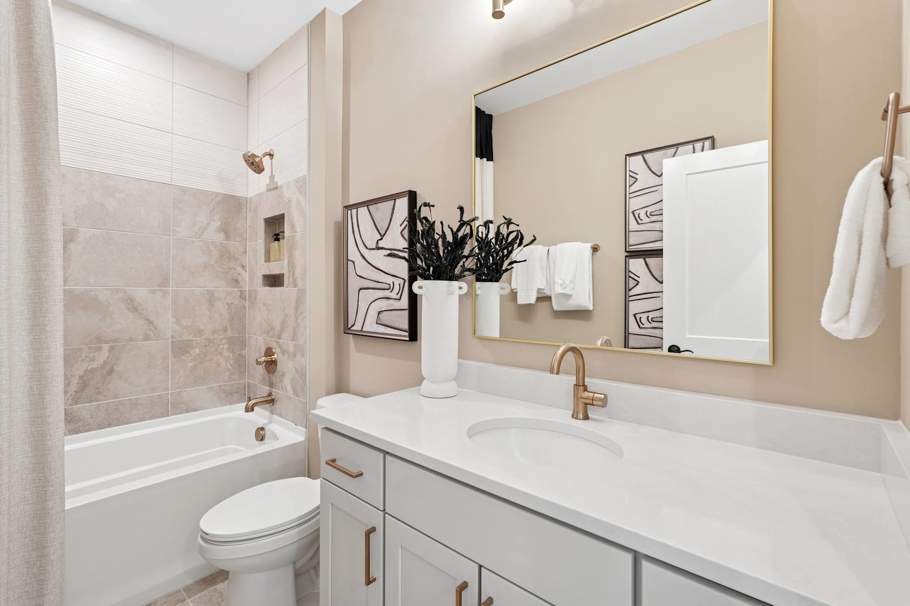 A modern and minimalist bathroom with a white vanity, a large mirror, and a framed artwork on the wall.