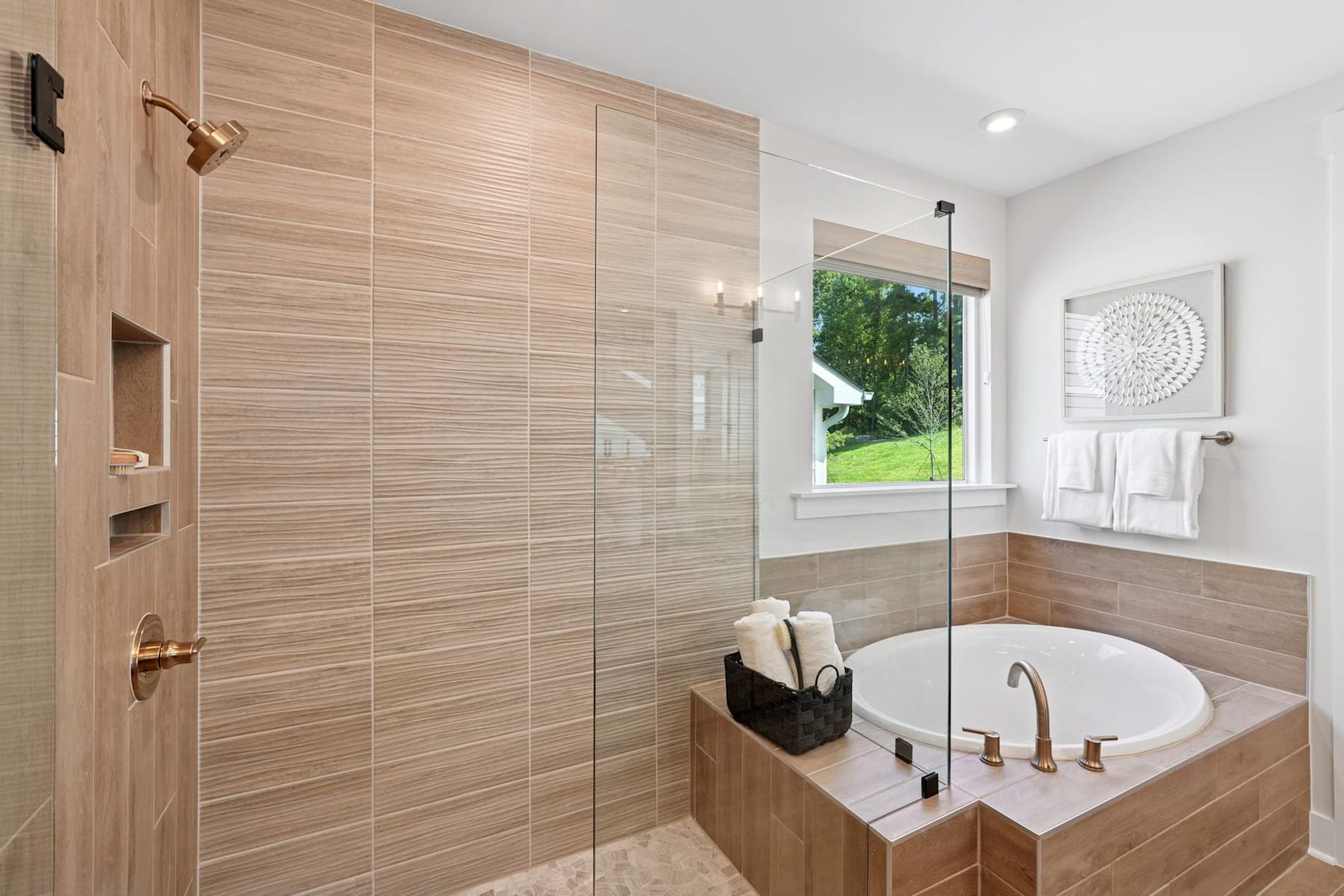 A modern and spacious bathroom with a large glass-enclosed shower, a freestanding bathtub, and a window overlooking a lush outdoor area.
