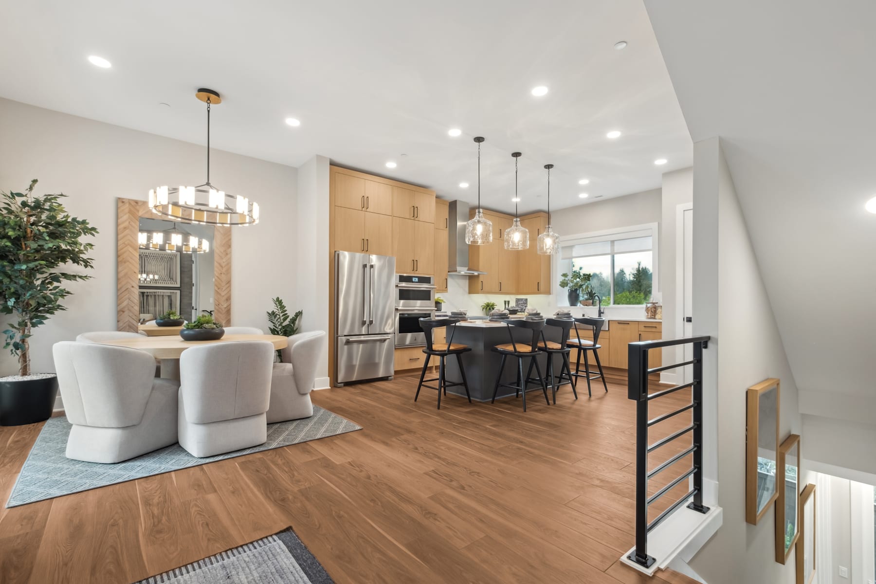 A modern and spacious kitchen with wooden cabinets, a large island, and a dining area with plush chairs, all illuminated by pendant lights and recessed lighting.