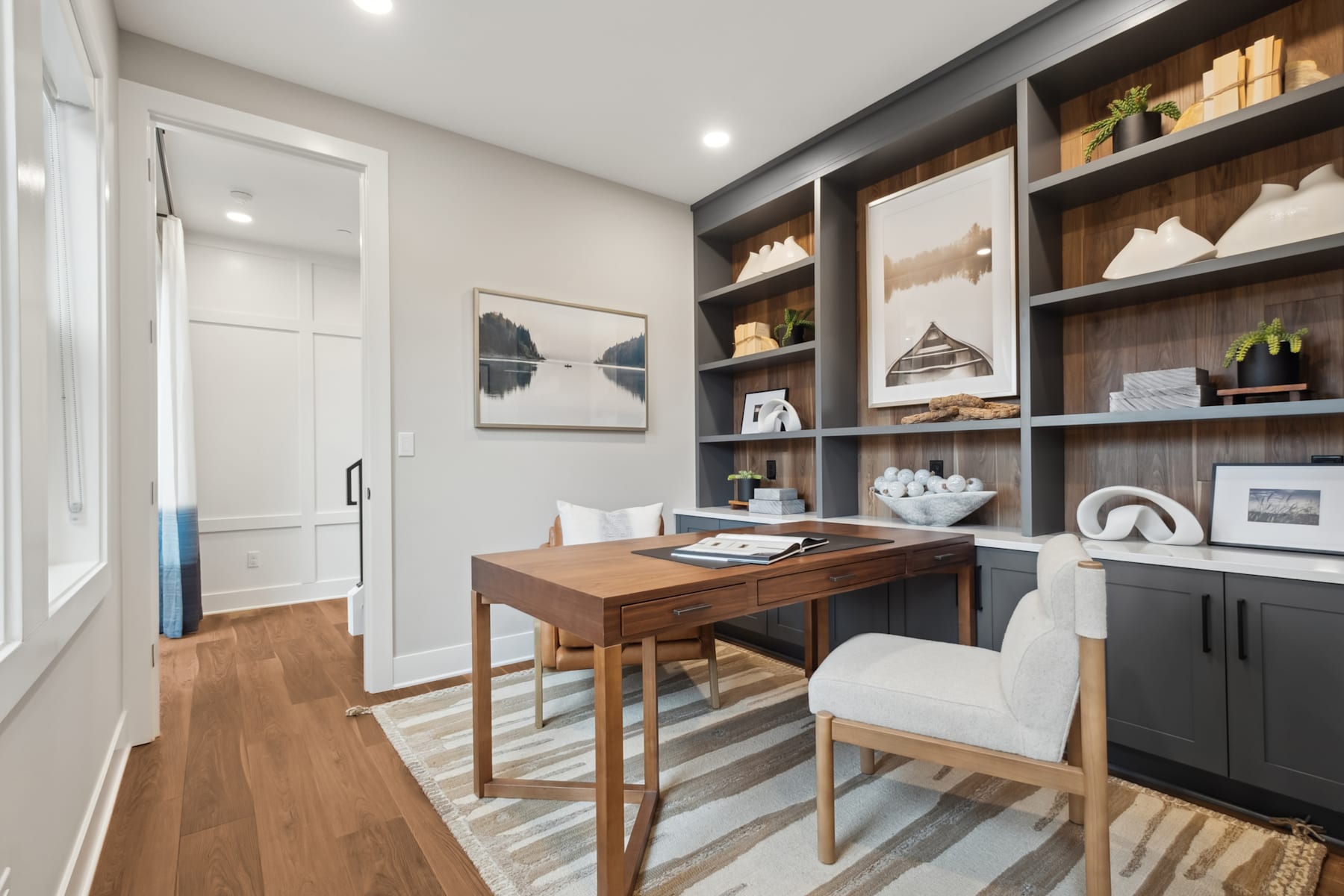 A cozy and well-organized home office space with a wooden desk, shelves displaying decorative items, and a neutral color scheme.