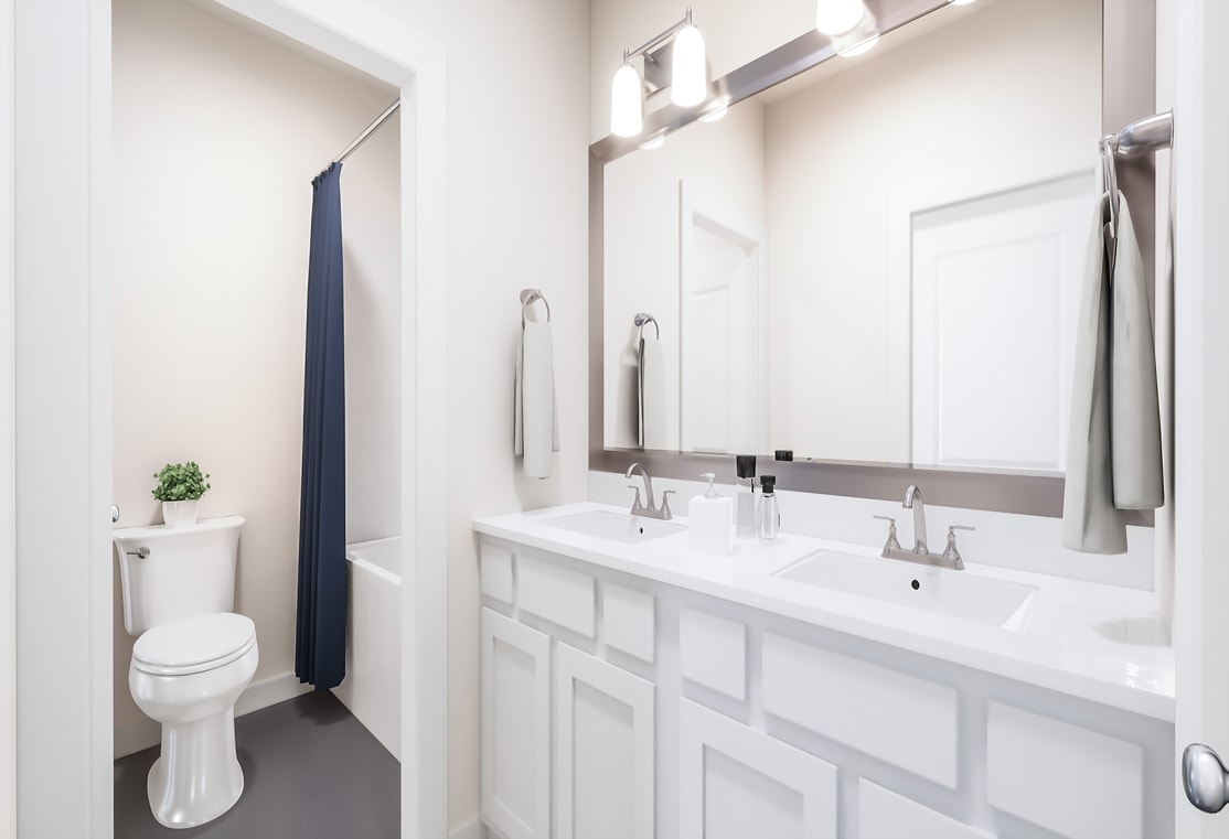 A modern, well-lit bathroom with a white vanity, a toilet, and a mirror on the wall.