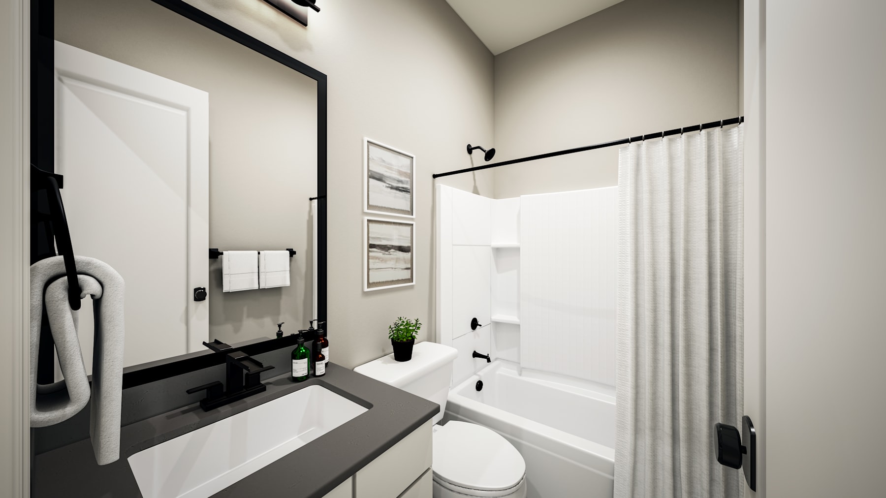 A modern, minimalist bathroom with a white bathtub, a black vanity, and framed artwork on the walls.