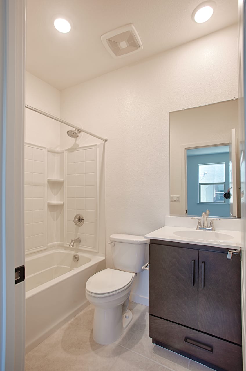 A modern and well-lit bathroom with a bathtub, toilet, and a vanity cabinet with a sink.