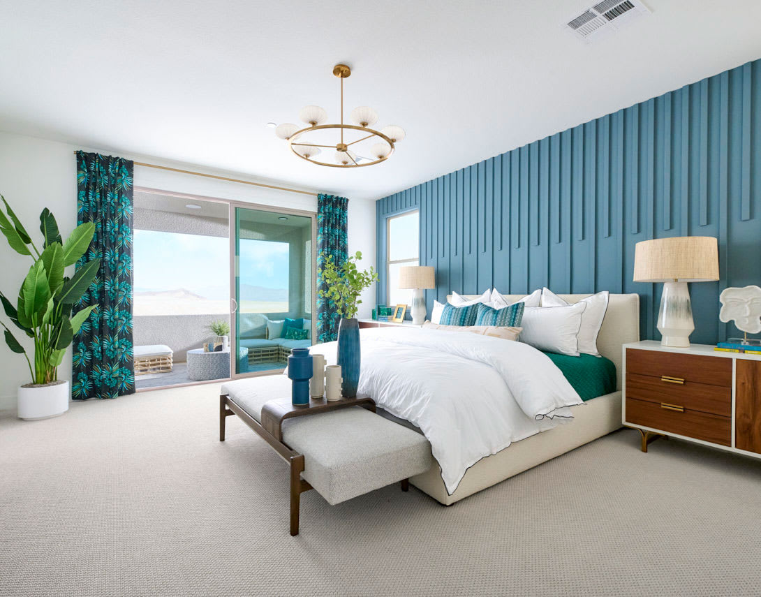 A spacious and elegantly designed bedroom with a blue accent wall, a large window overlooking a scenic view, and a cozy seating area in the foreground.