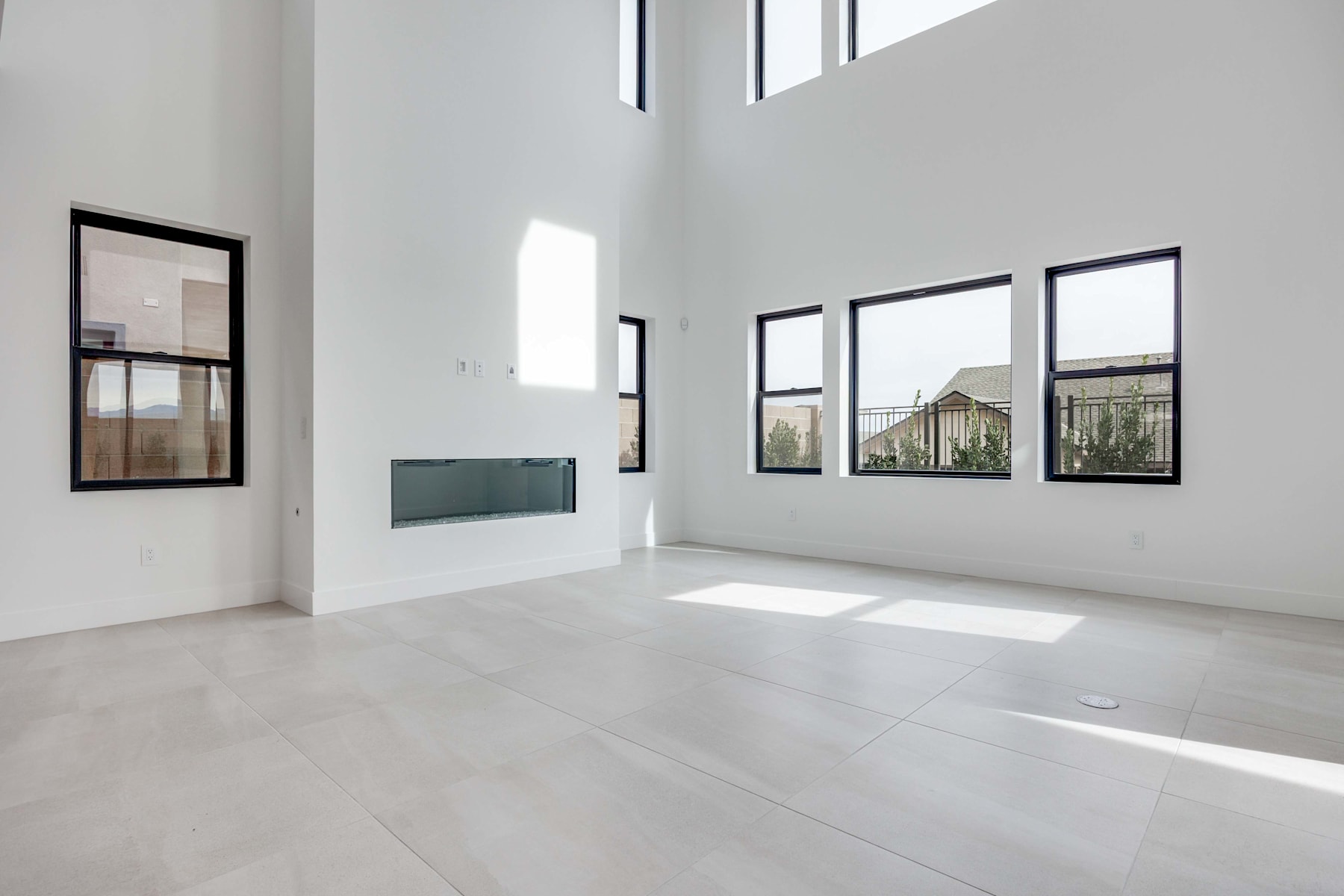 A spacious, minimalist interior with large windows allowing natural light to flood the room, creating a bright and airy atmosphere.
