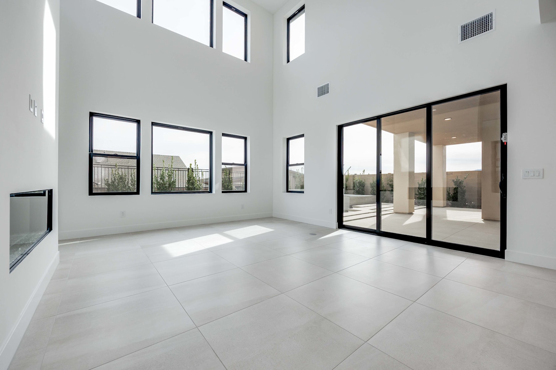A spacious, minimalist interior with large windows, clean white walls, and a tiled floor, creating a bright and airy atmosphere.