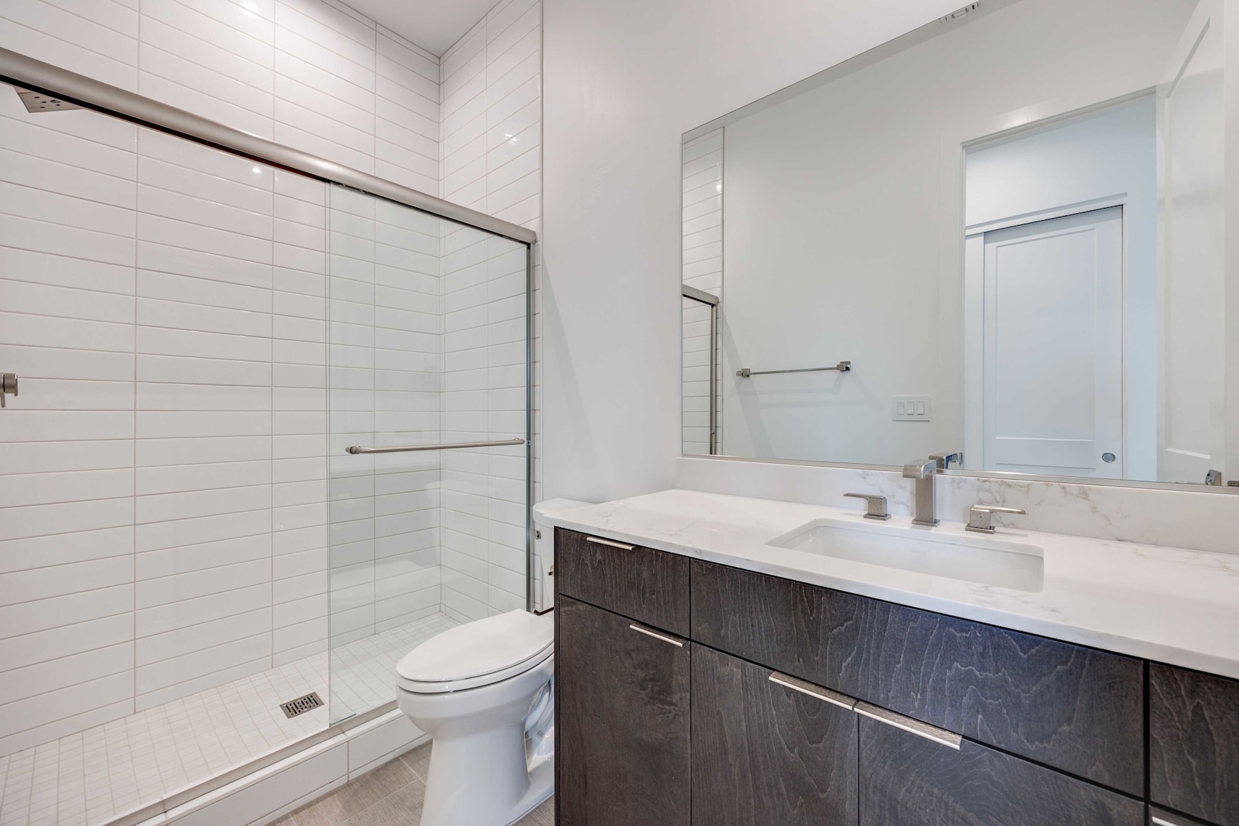 A modern bathroom with a vanity cabinet, a sink, and a shower enclosure, all in a clean and minimalist design.