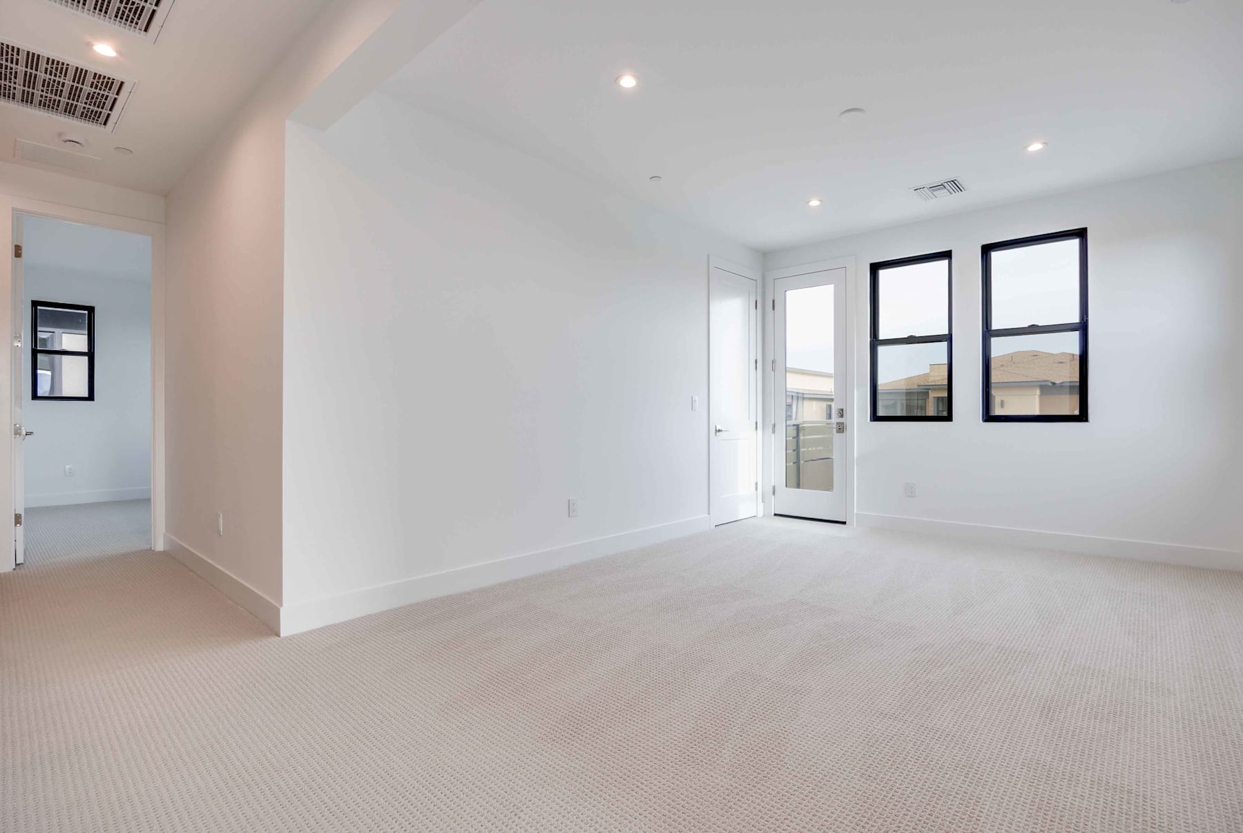 A bright, spacious room with white walls, hardwood floors, and large windows providing ample natural light.