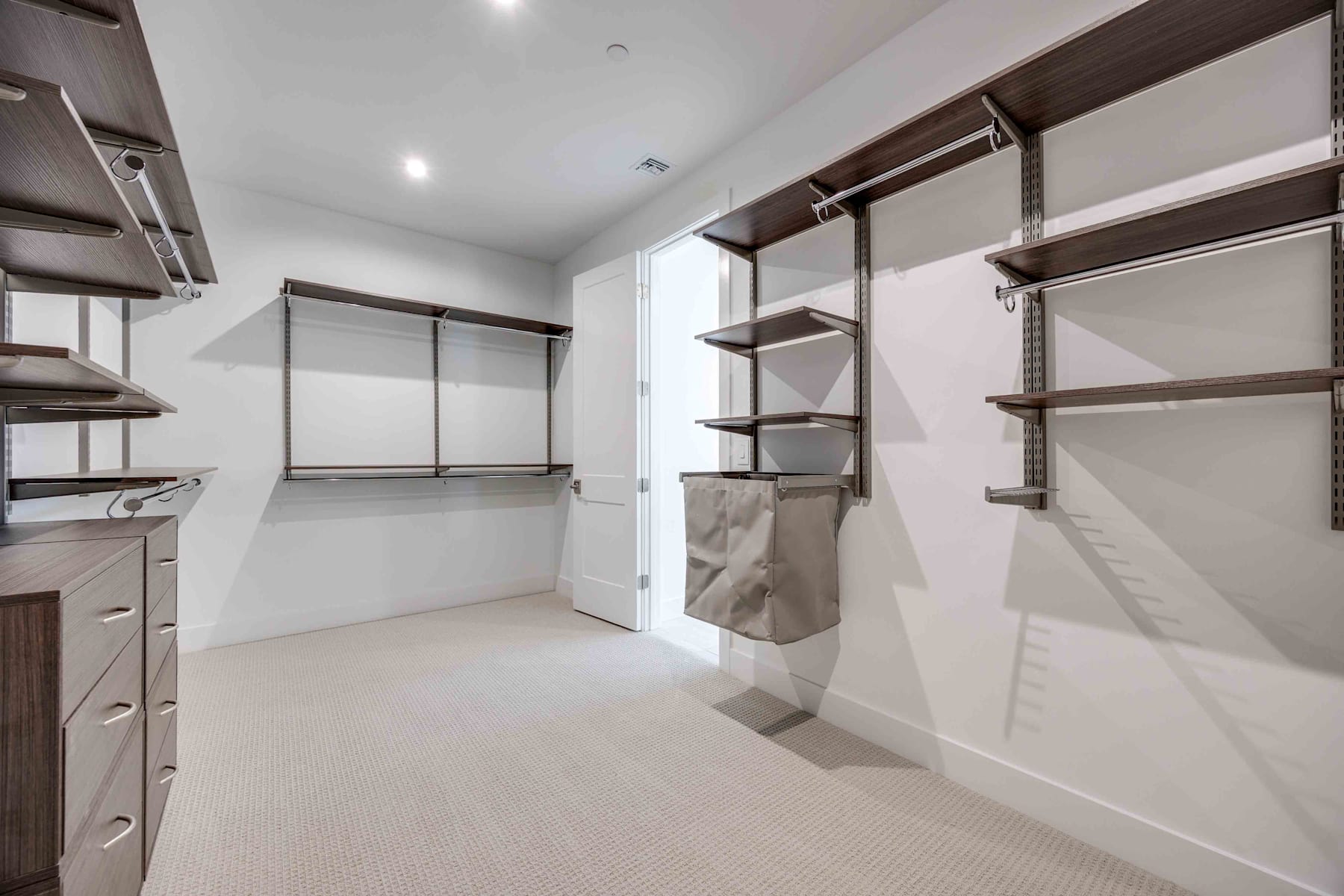 A spacious and well-organized walk-in closet with ample shelving, hanging rods, and drawers, providing an efficient storage solution in a bright and clean environment.