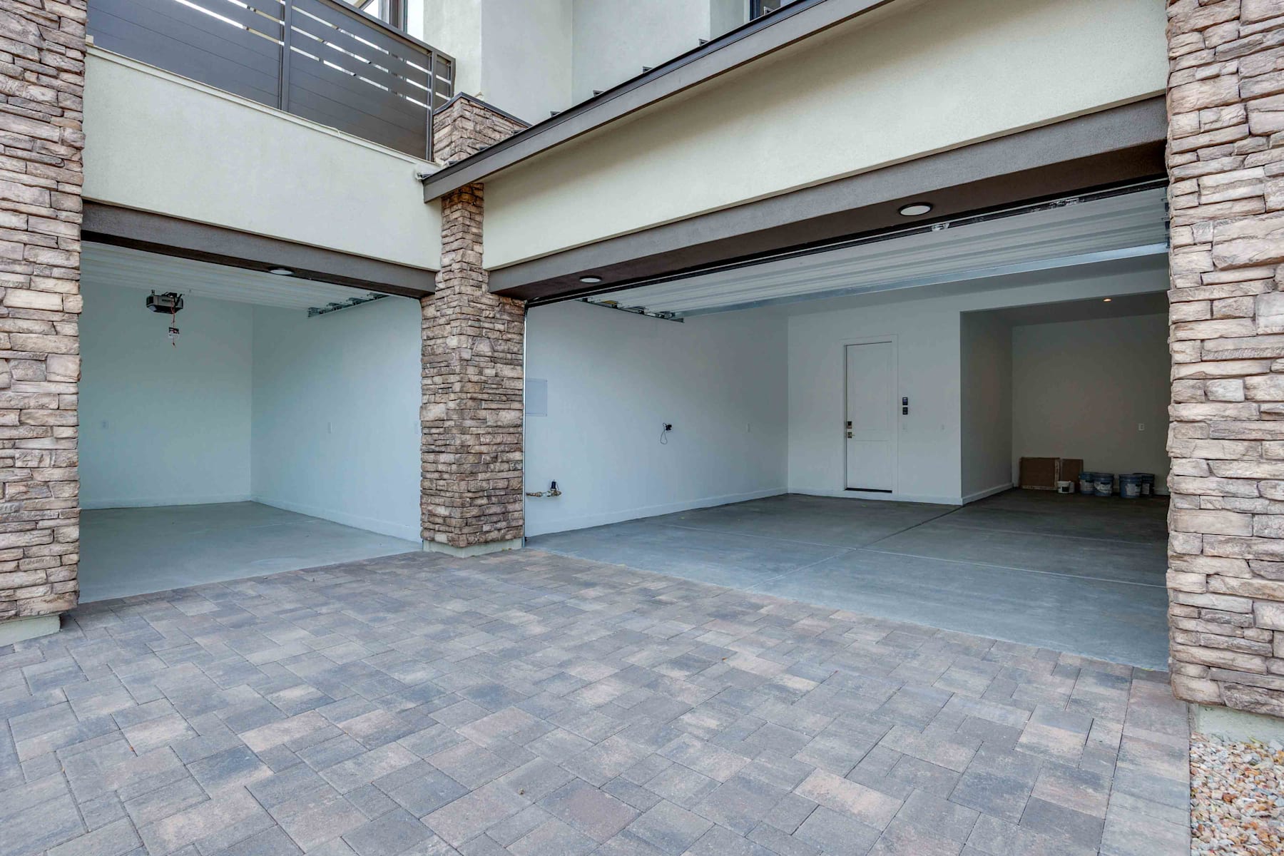A spacious, modern interior with a tiled floor, stone walls, and large glass doors leading to an outdoor area.