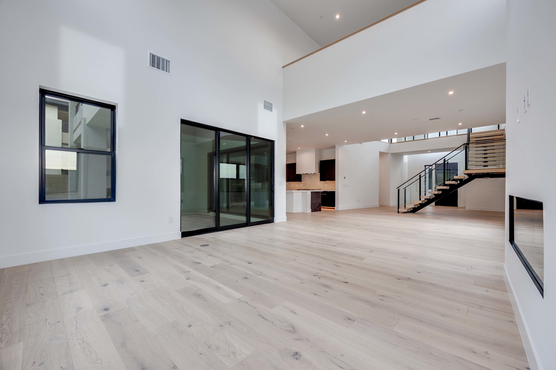 A spacious, modern interior with large windows, hardwood floors, and a minimalist design aesthetic.