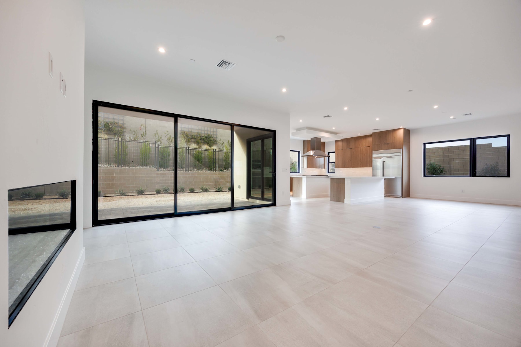 A spacious, modern interior with a large open floor plan, featuring wooden cabinetry, floor-to-ceiling windows, and a clean, minimalist design.