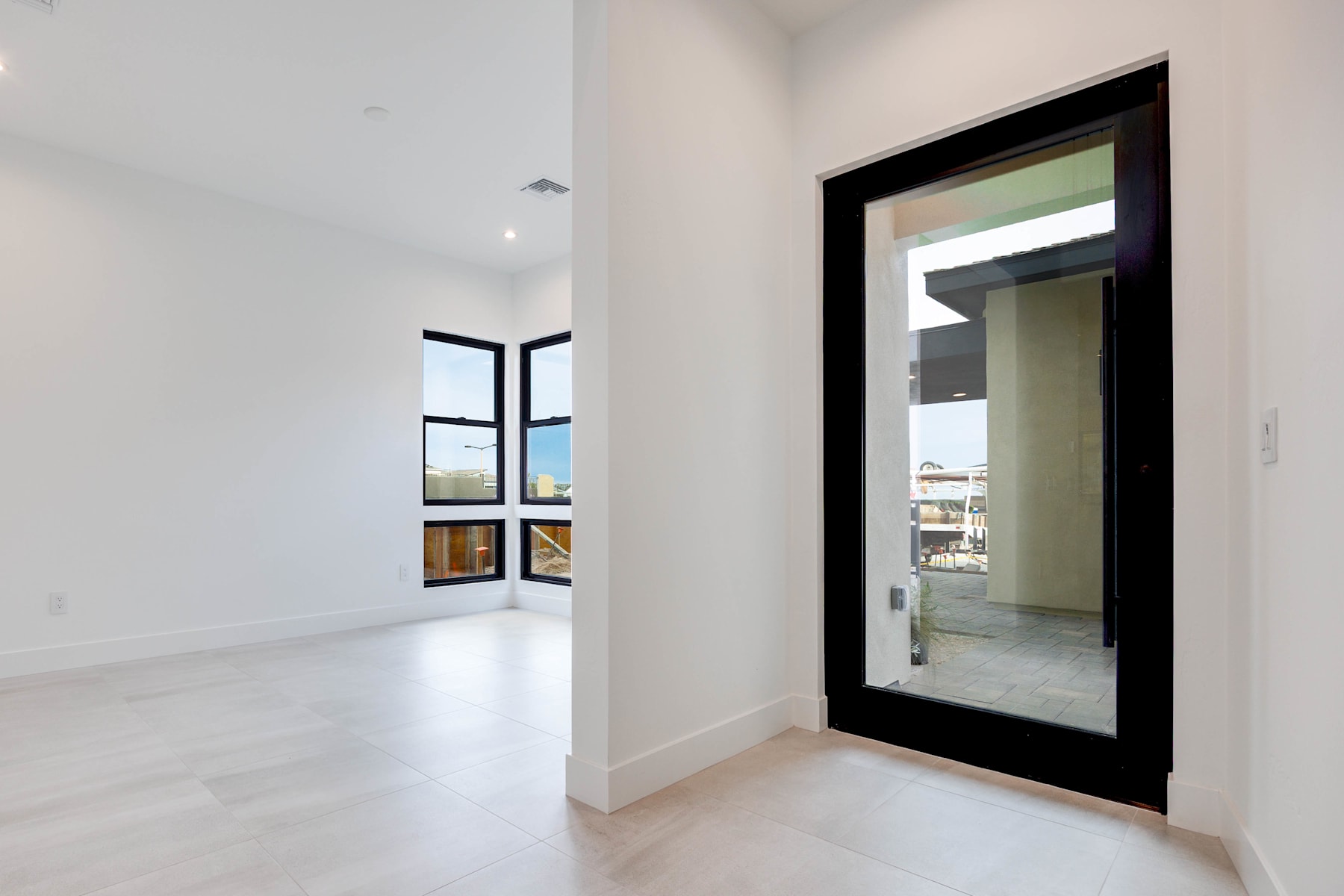 A spacious, minimalist interior with a large black-framed mirror reflecting the view through the window in the background.