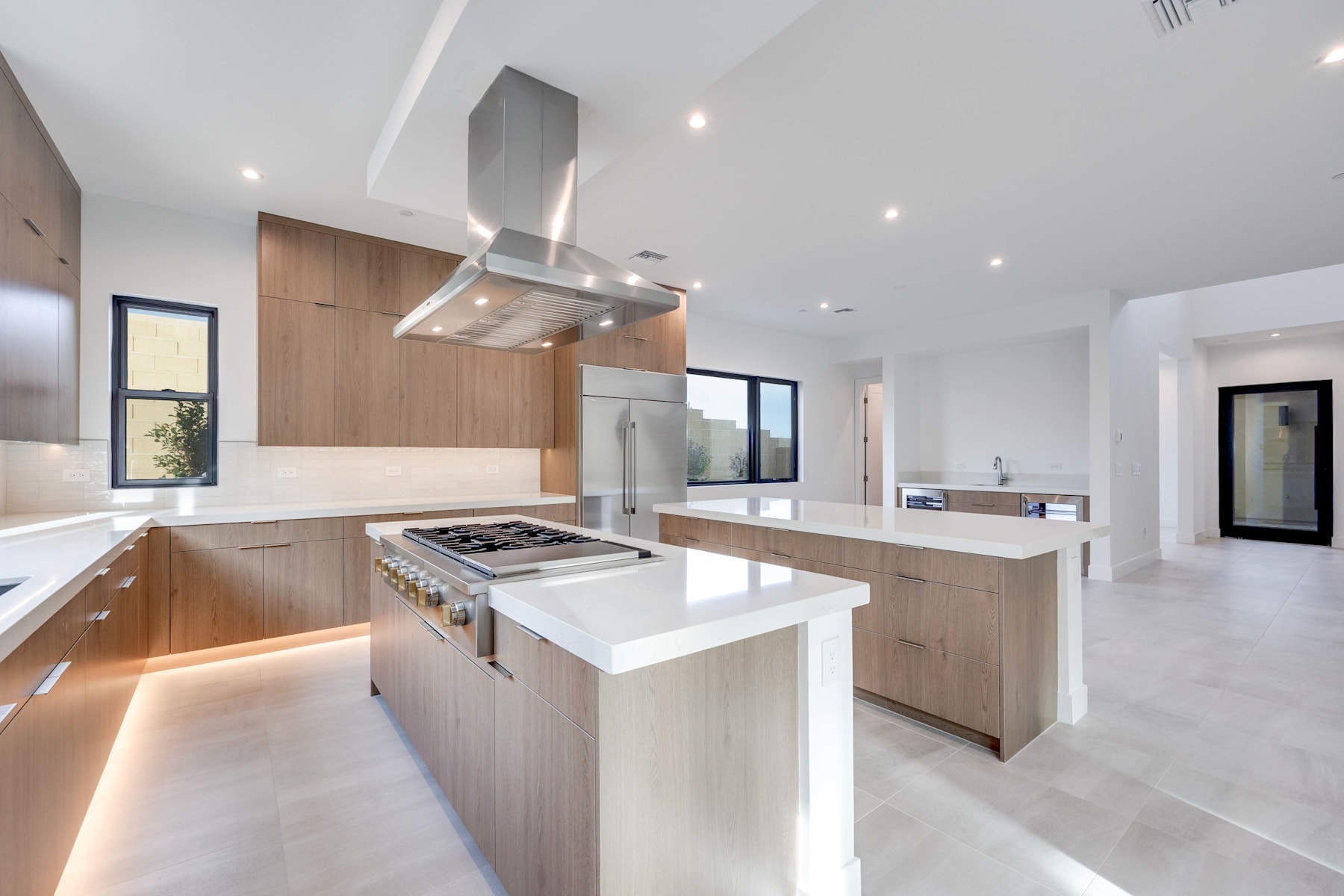 A modern, open-concept kitchen with sleek, light-colored cabinetry, a large island, and stainless steel appliances, set against a bright, airy backdrop.