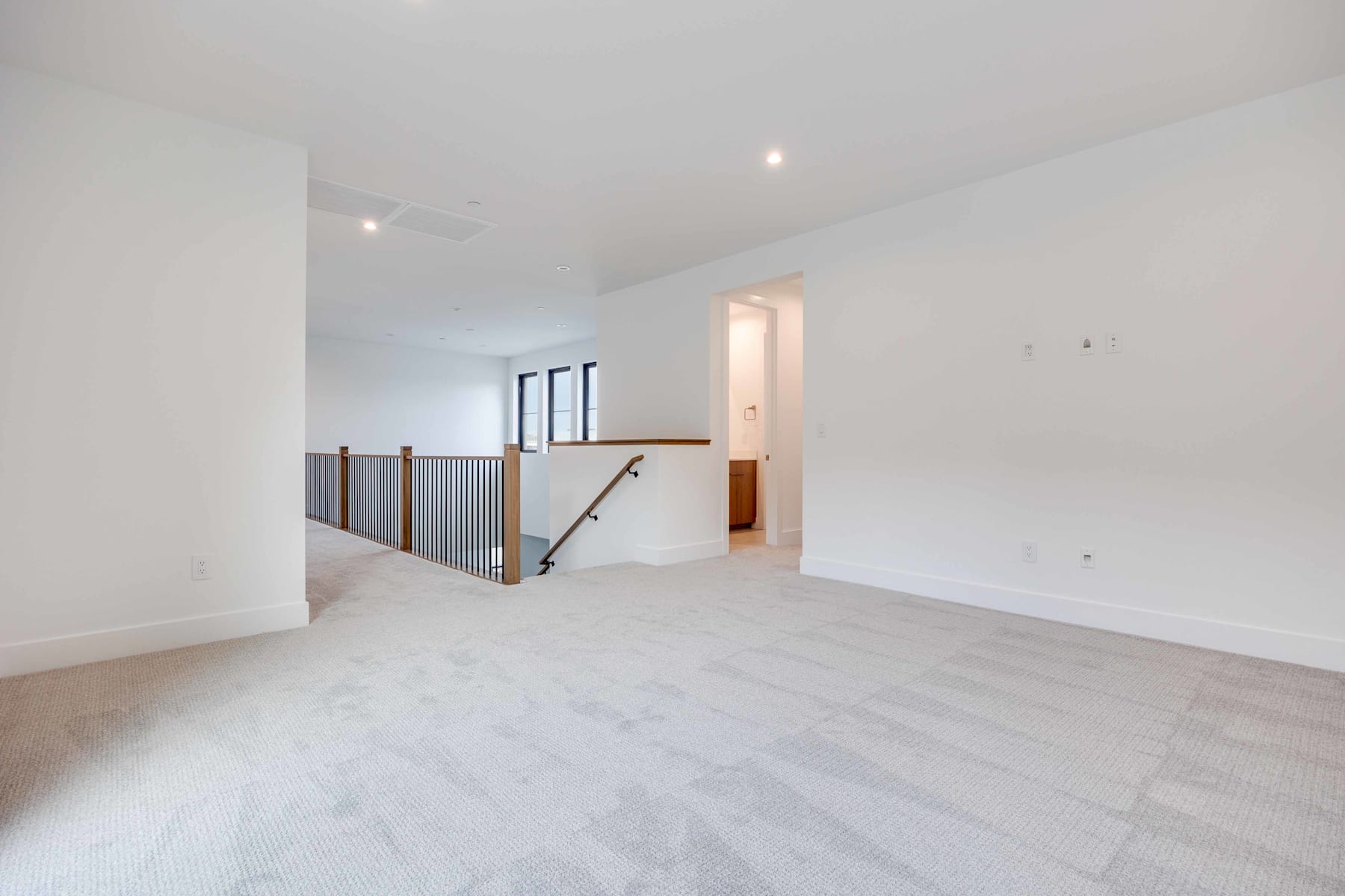 A spacious, minimalist interior with white walls, wooden railings, and a clean, uncluttered floor.