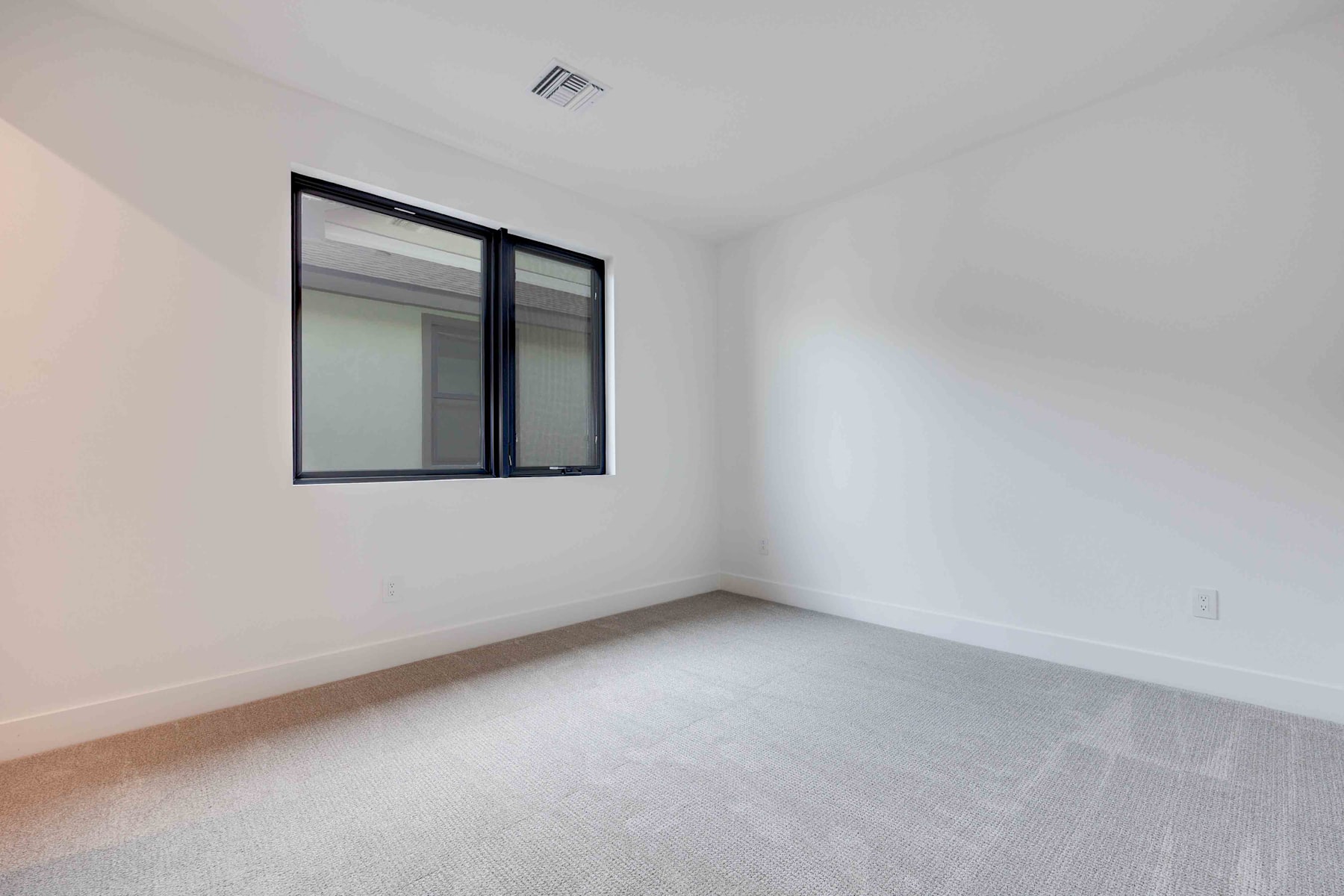 A simple, minimalist room with a large window and bare walls, creating a clean and open atmosphere.