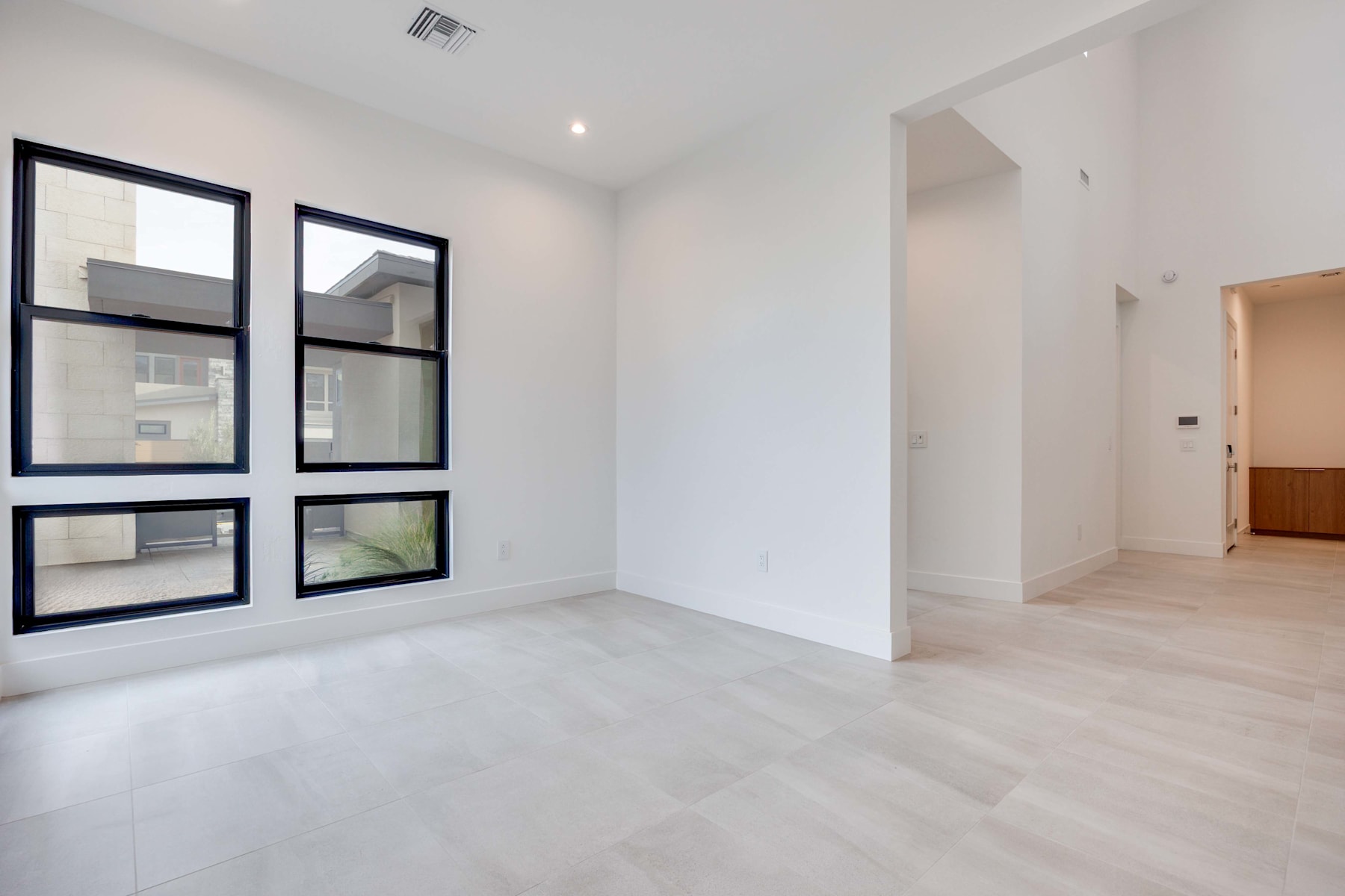 A spacious, minimalist room with white walls, wooden floors, and framed artwork on the walls.