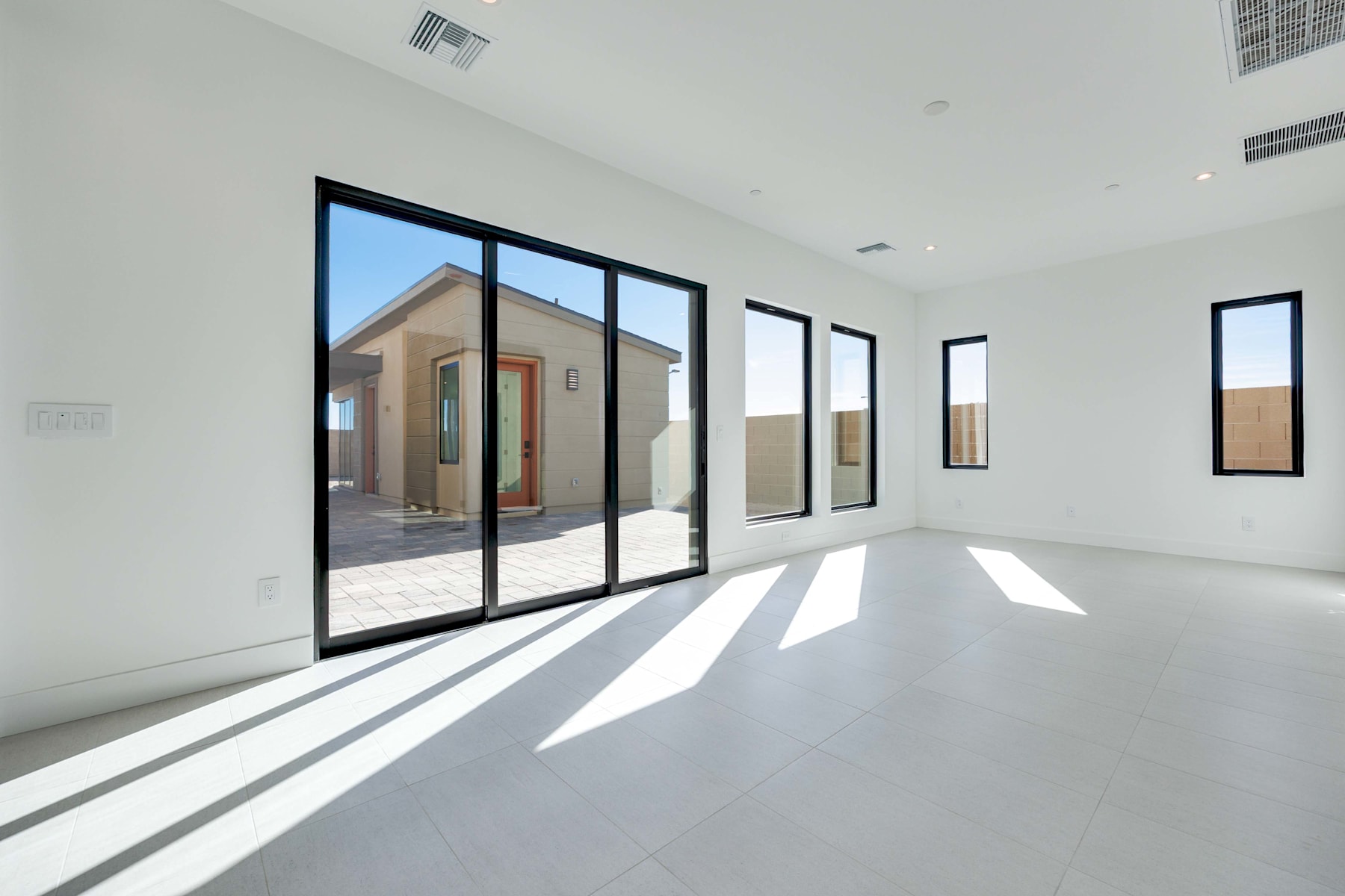 A spacious, minimalist interior with large windows allowing ample natural light to fill the room, creating a bright and airy atmosphere.