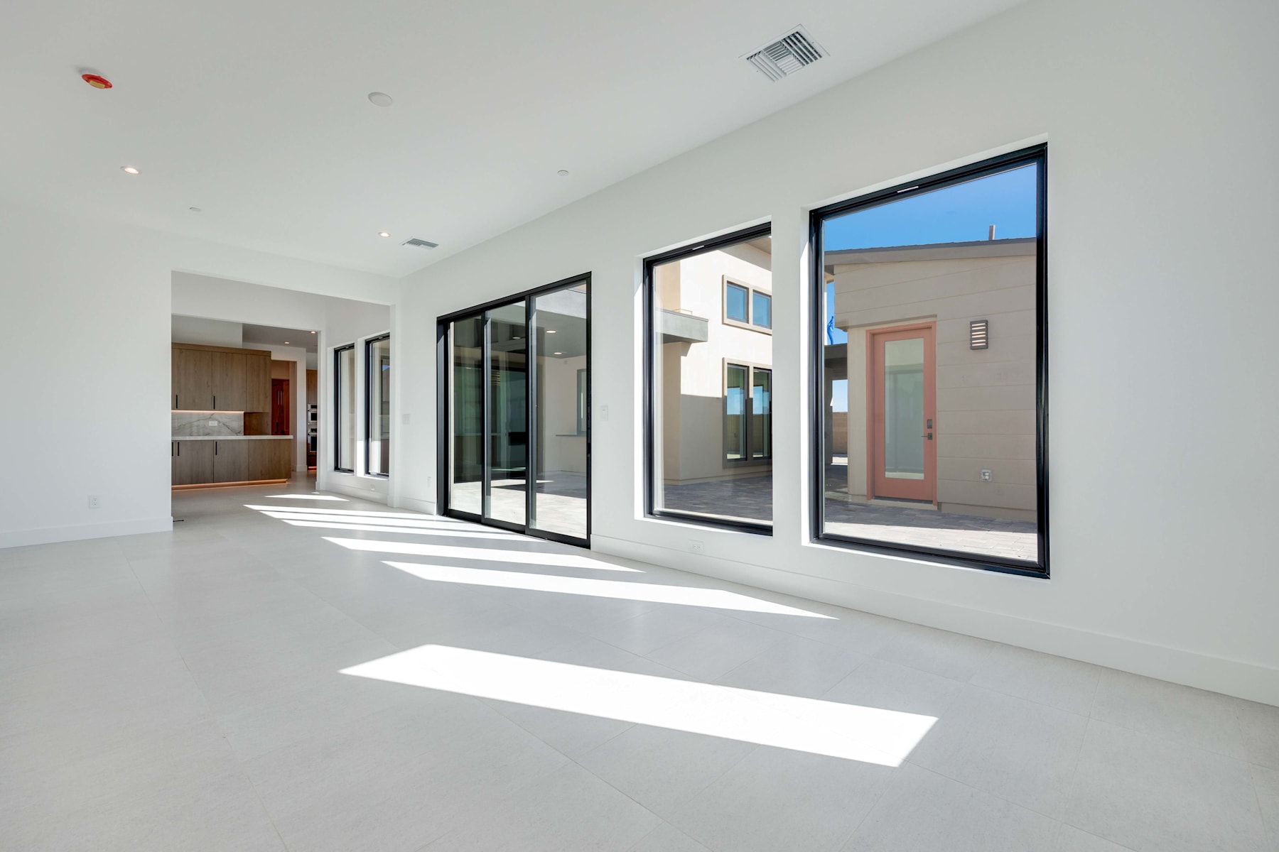 A spacious, modern interior with large windows overlooking the exterior, featuring a clean, minimalist design with a smooth, light-colored floor.