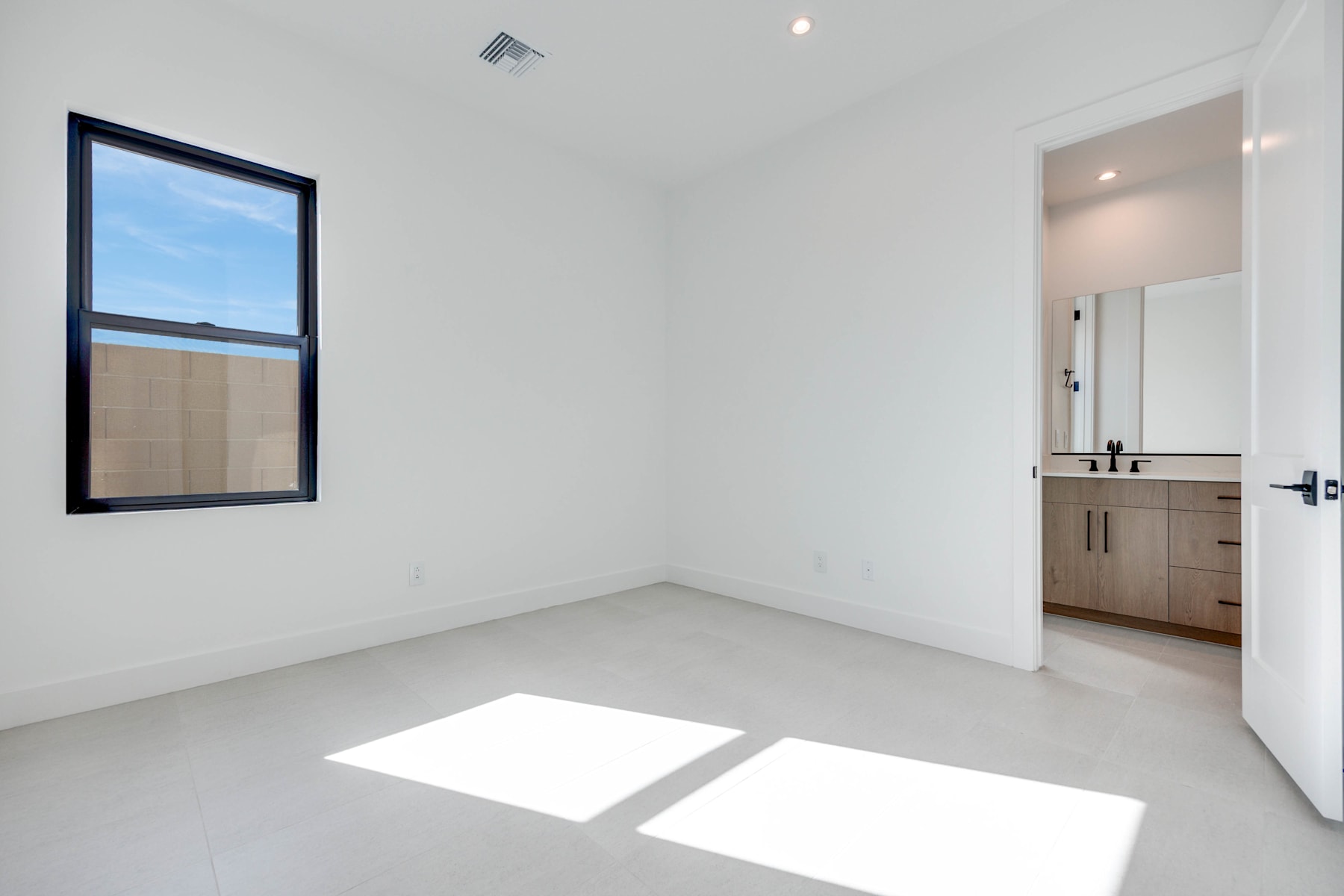 A minimalist, well-lit room with a large window, a vanity, and a clean, uncluttered interior design.