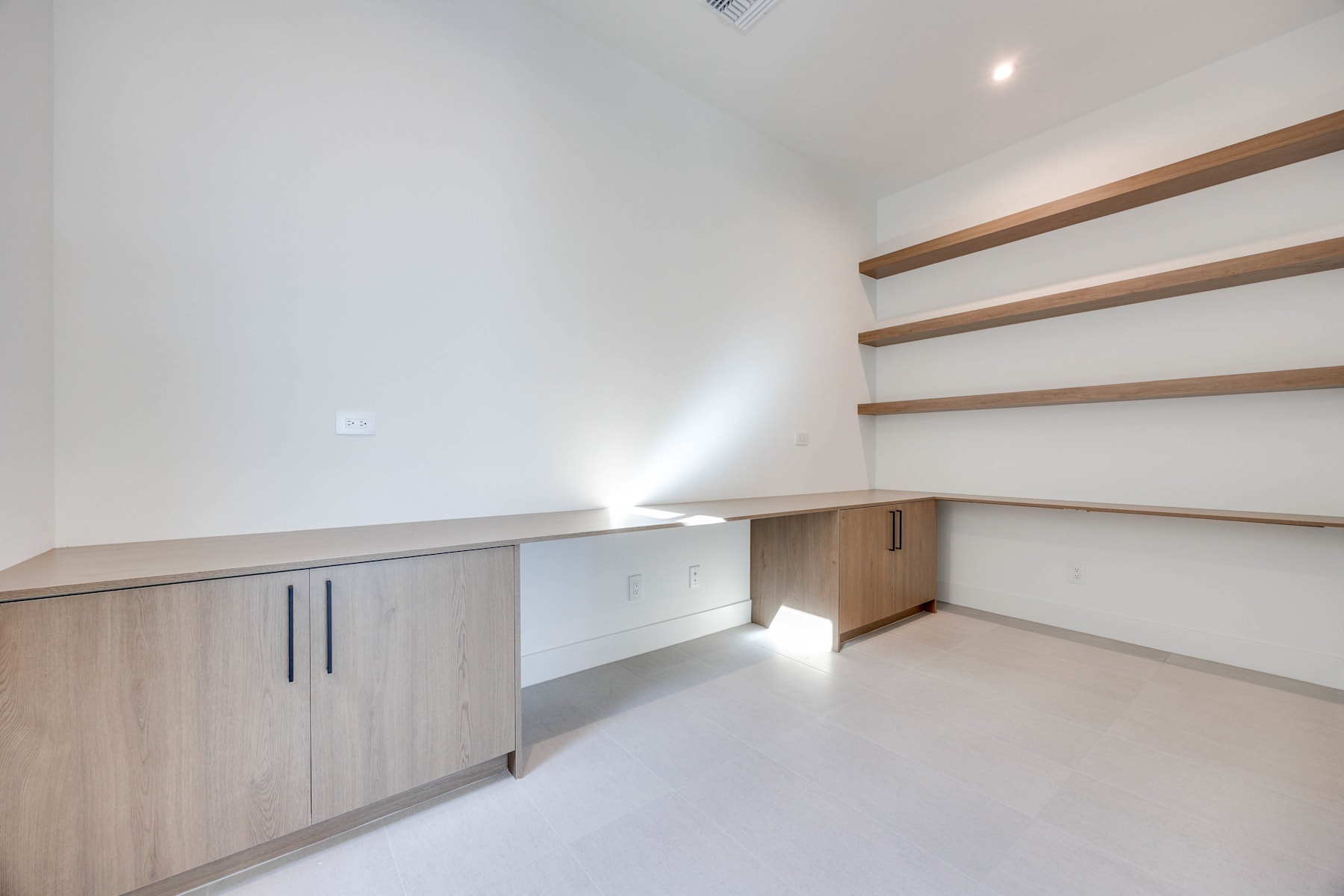 A minimalist and well-organized room with wooden shelves and cabinets, providing ample storage space and a clean, uncluttered aesthetic.