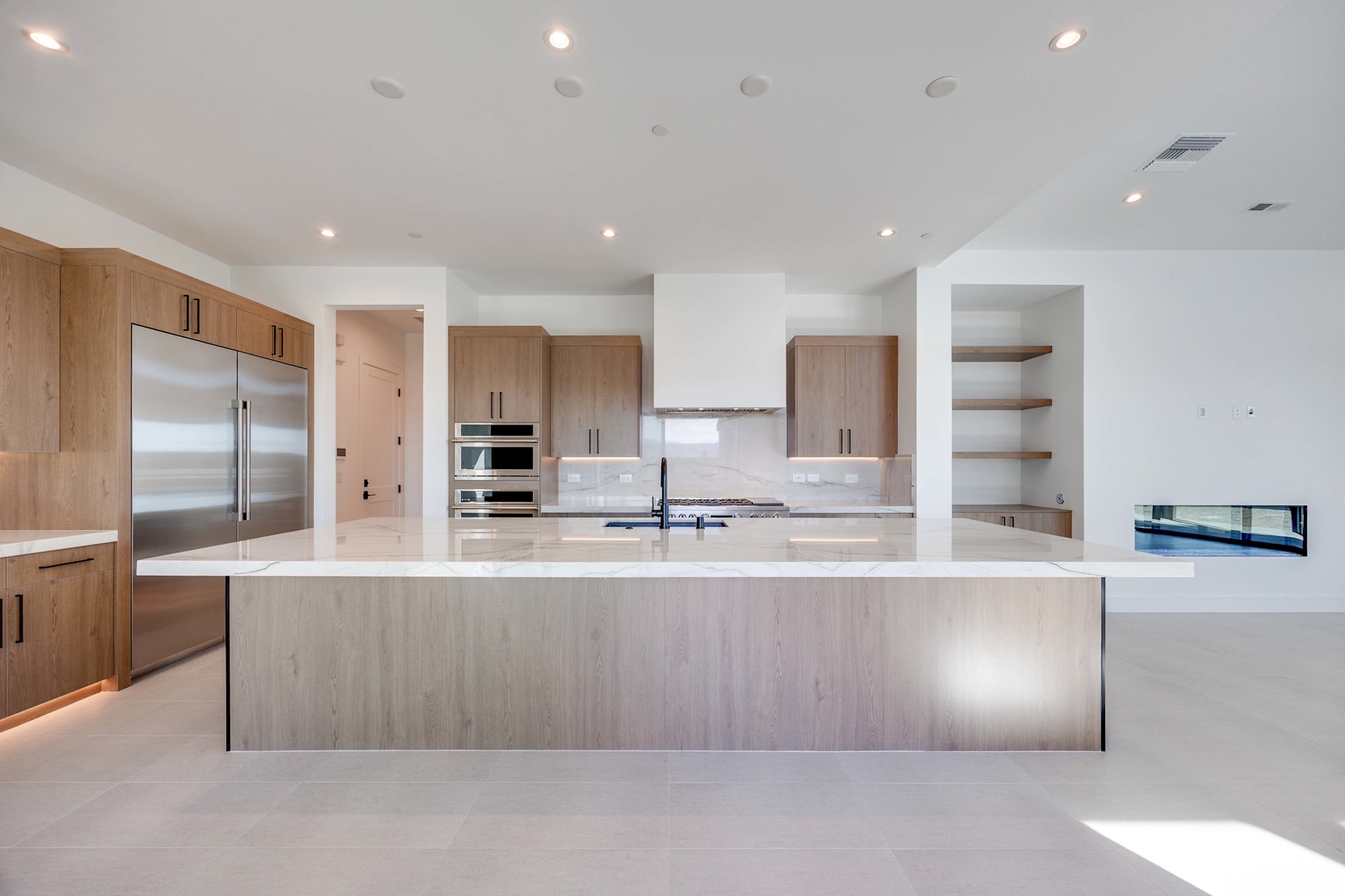 A modern, open-concept kitchen with a large central island, stainless steel appliances, and ample natural lighting.