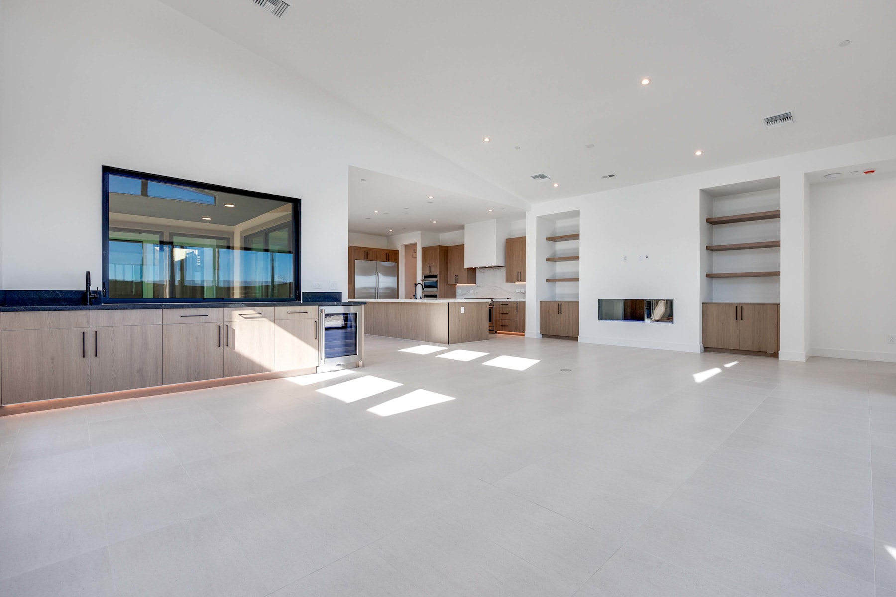 A spacious, modern kitchen and living area with large windows offering a scenic view of the outdoors.