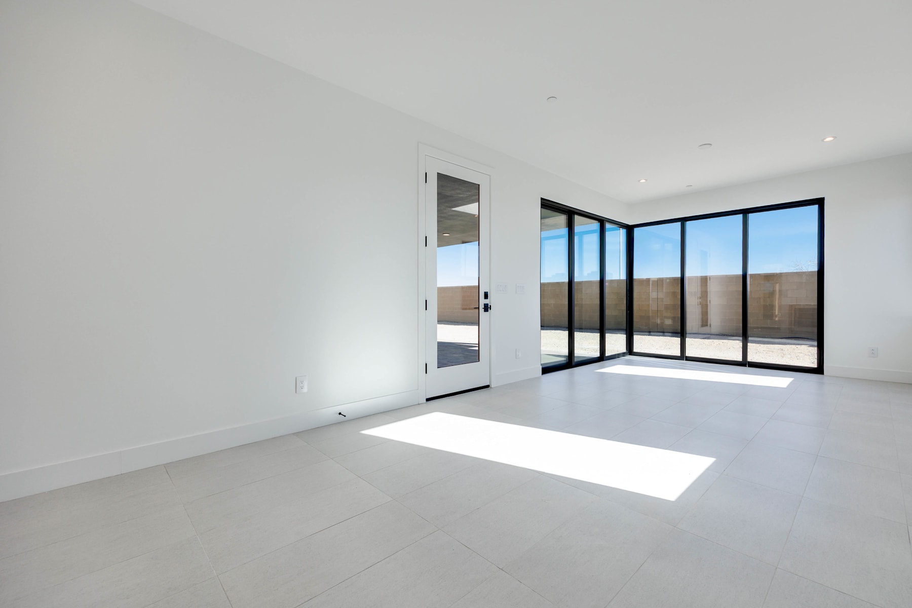 A bright, minimalist interior space with large windows overlooking an outdoor area.