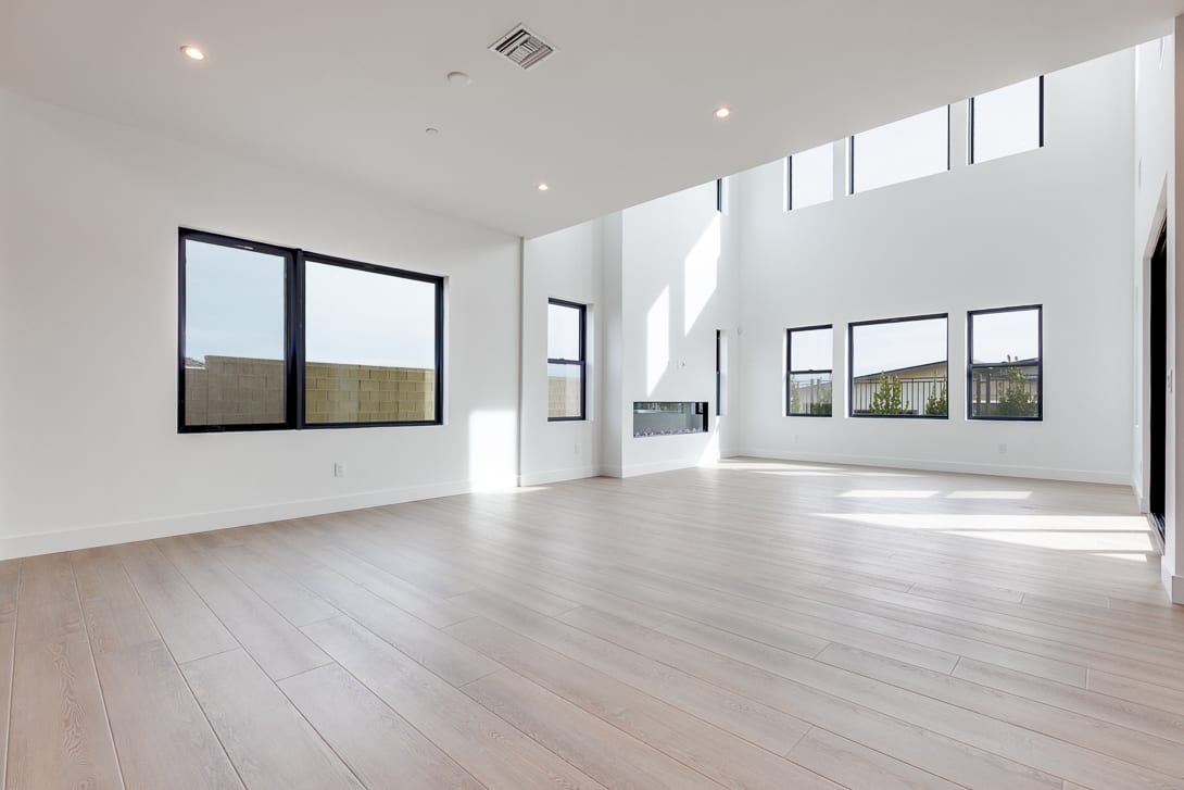 A spacious, well-lit room with large windows, hardwood floors, and a minimalist design aesthetic.