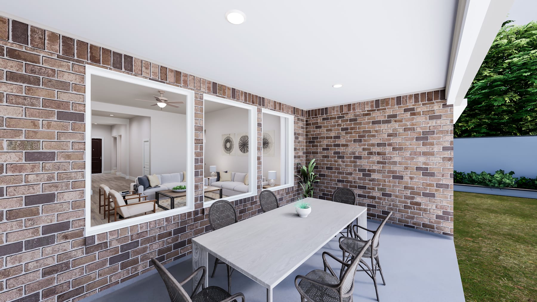 A covered outdoor patio with a brick wall, a table, and chairs, surrounded by greenery.
