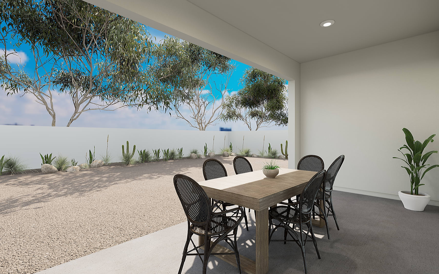 A modern outdoor dining area with a wooden table and black chairs, surrounded by a desert landscape with cacti and trees against a blue sky.
