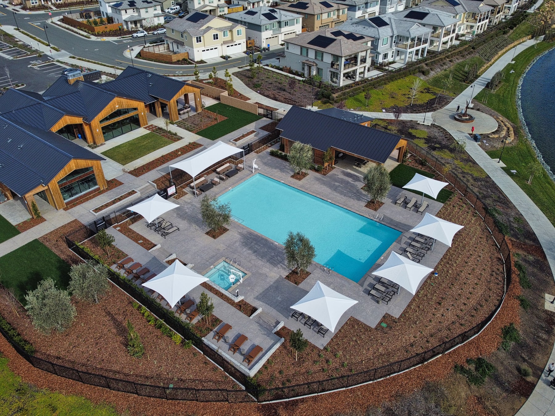A residential community with a central swimming pool surrounded by various houses, patios, and landscaped areas.