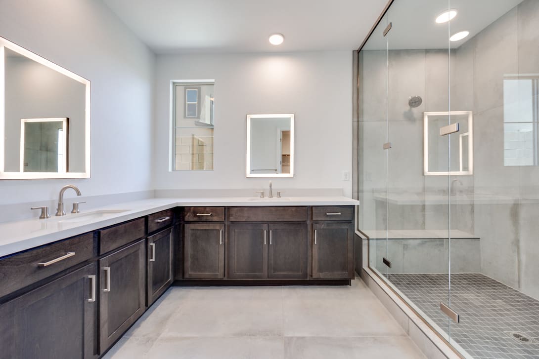 A modern and spacious bathroom with dark wood cabinets, a large vanity, and a glass-enclosed shower area.