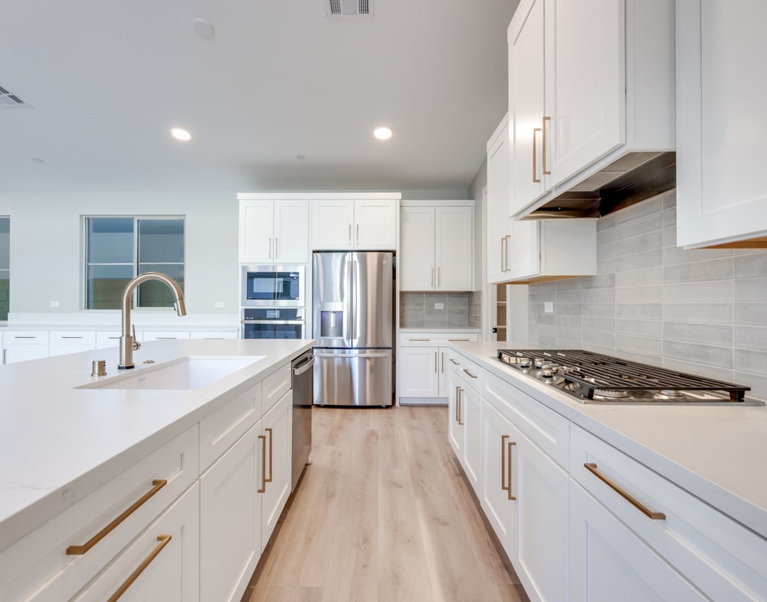 A modern, bright kitchen with white cabinets, stainless steel appliances, and a sleek, minimalist design.