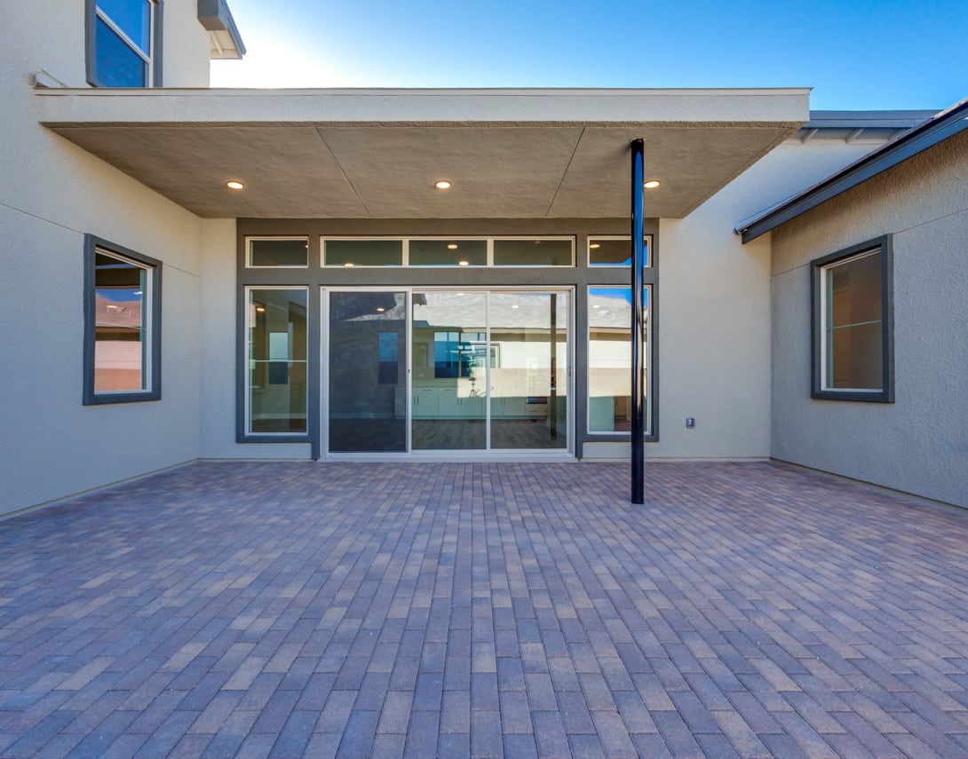 A modern, two-story building with a covered entryway and a paved brick walkway leading to the entrance. The building features large windows and a clean, minimalist design.
