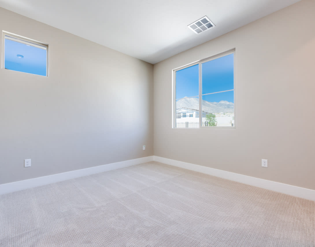 A spacious, bright room with large windows overlooking a residential neighborhood in the background.