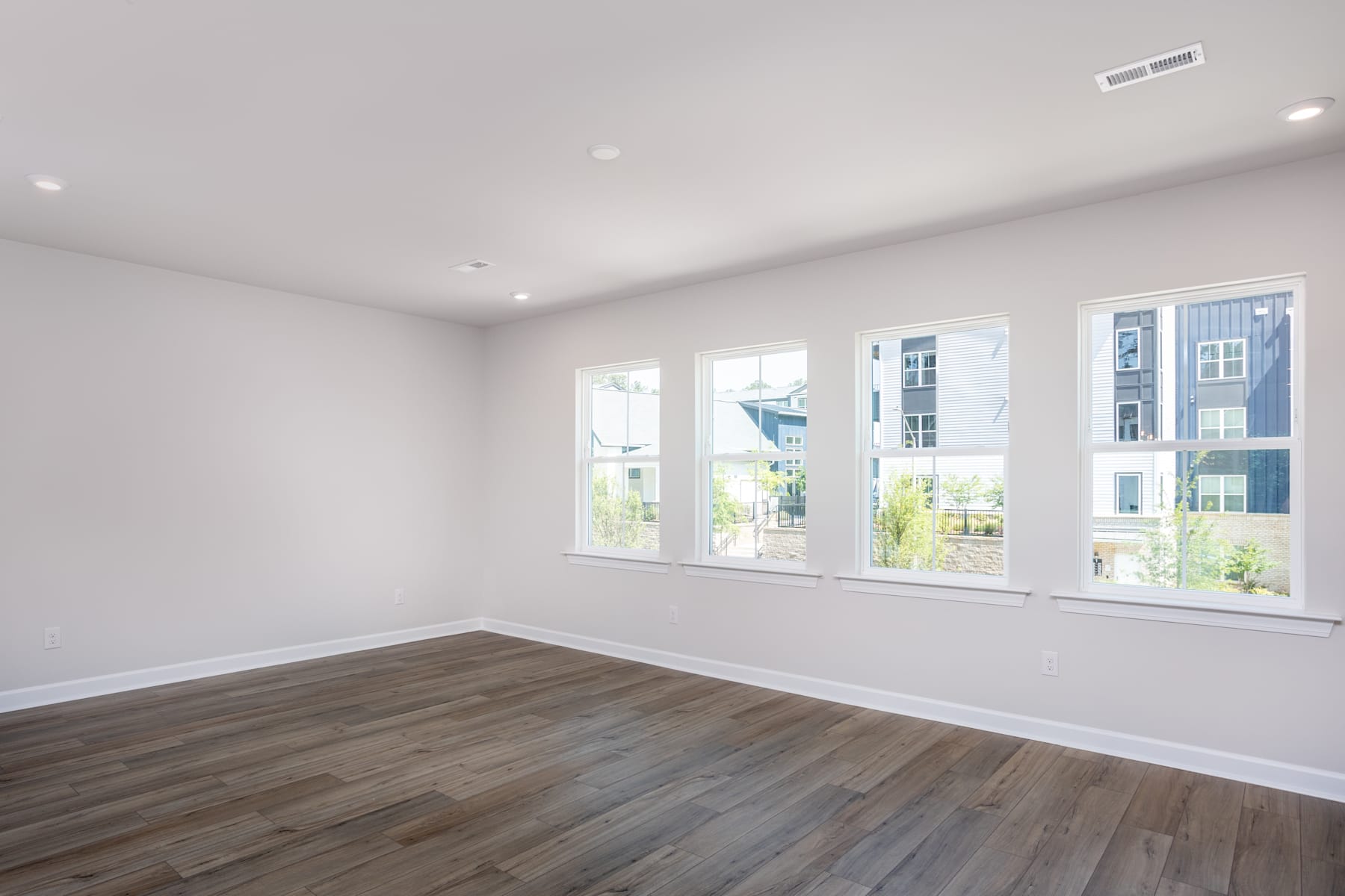 A bright and spacious room with large windows, hardwood floors, and a clean, minimalist design.
