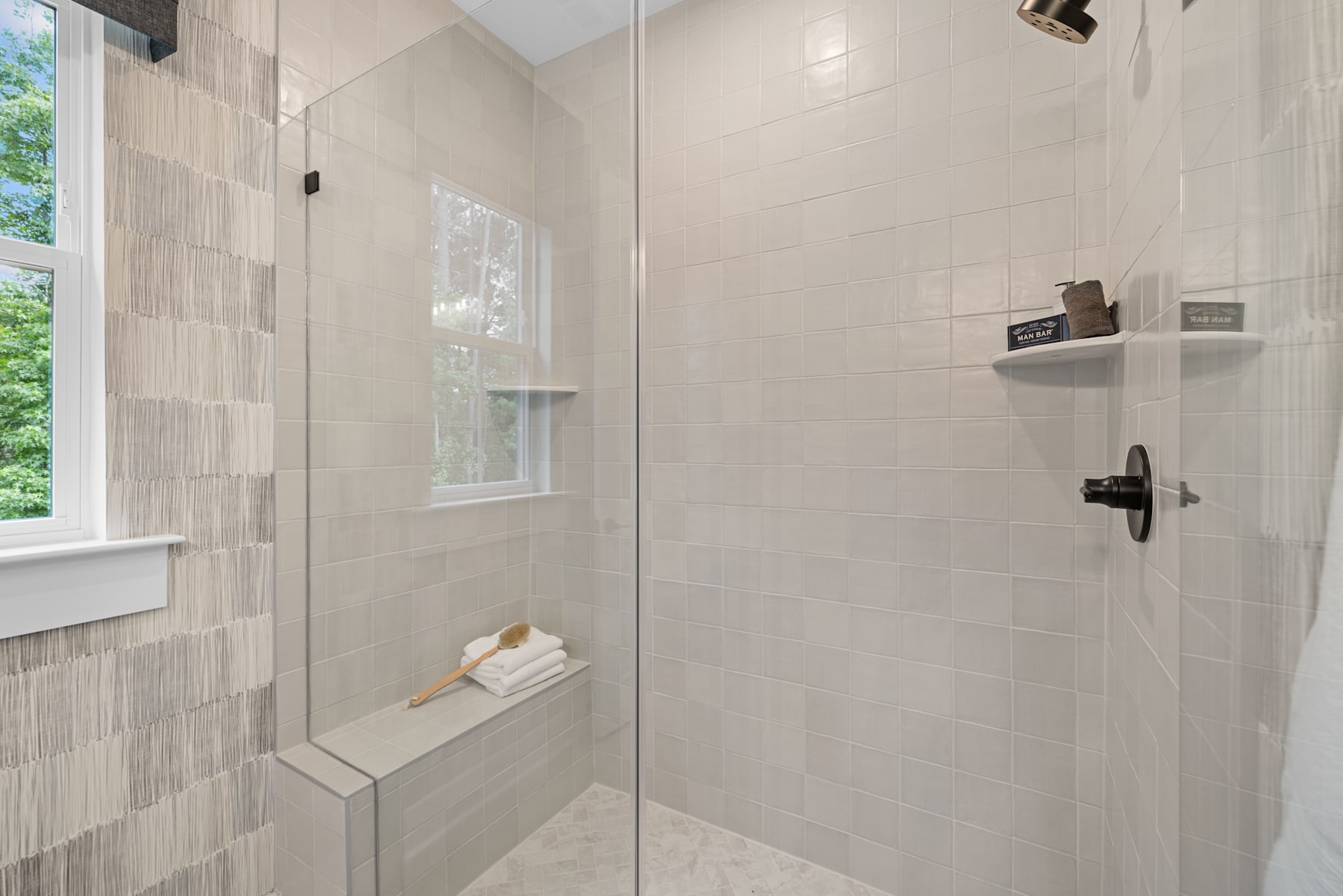 A spacious and modern bathroom with a large window, tiled walls, and a built-in shower bench.