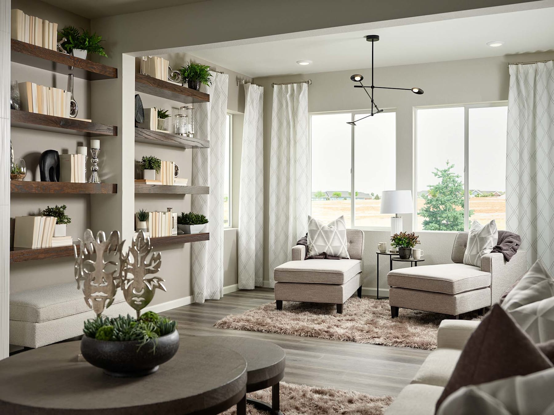 A cozy and inviting living room with a round wooden coffee table, plush seating, and built-in shelving displaying various decorative items and plants, all set against a backdrop of large windows overlooking a scenic outdoor view.