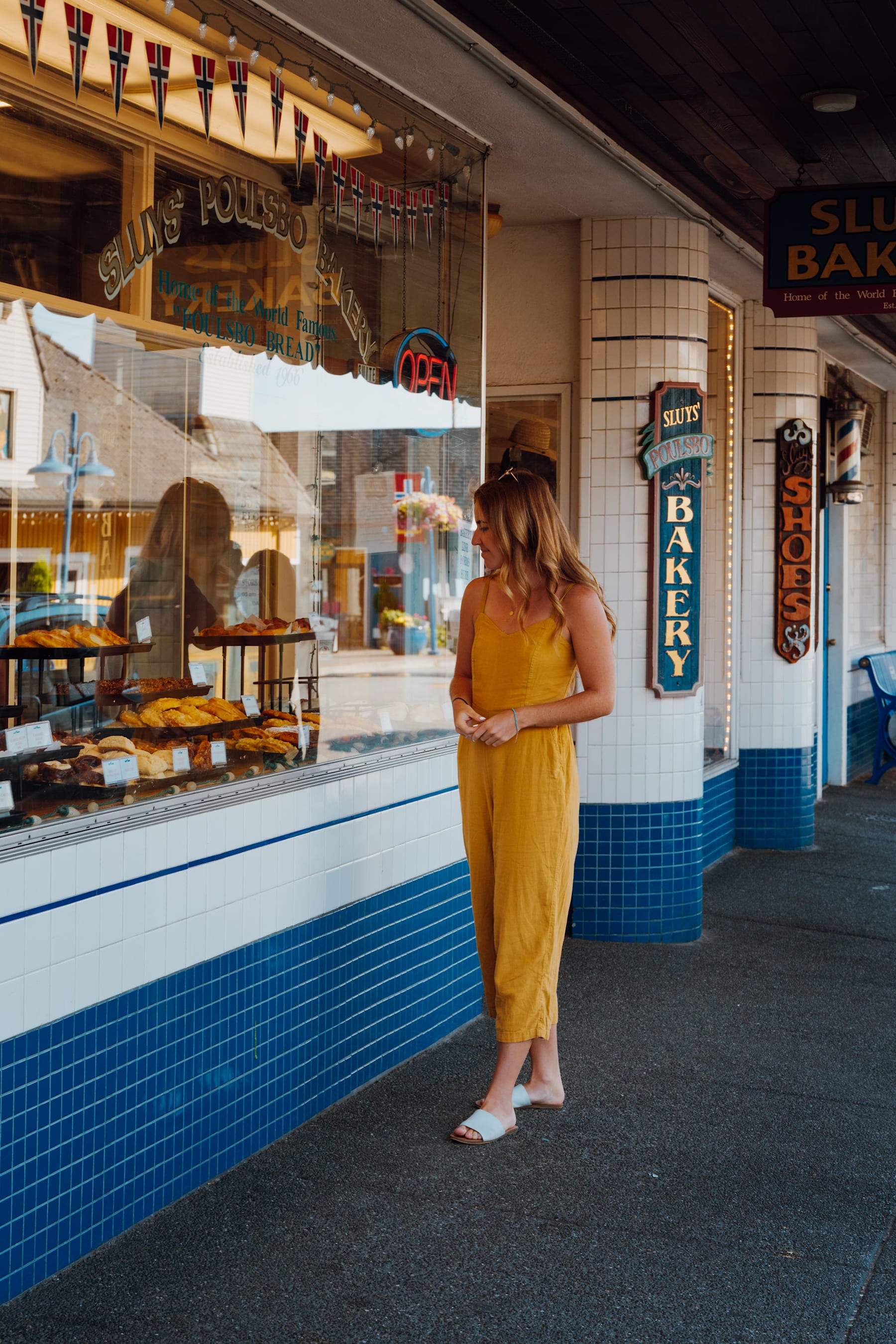 A woman in a yellow dress stands in front of a colorful storefront with various signs and displays.