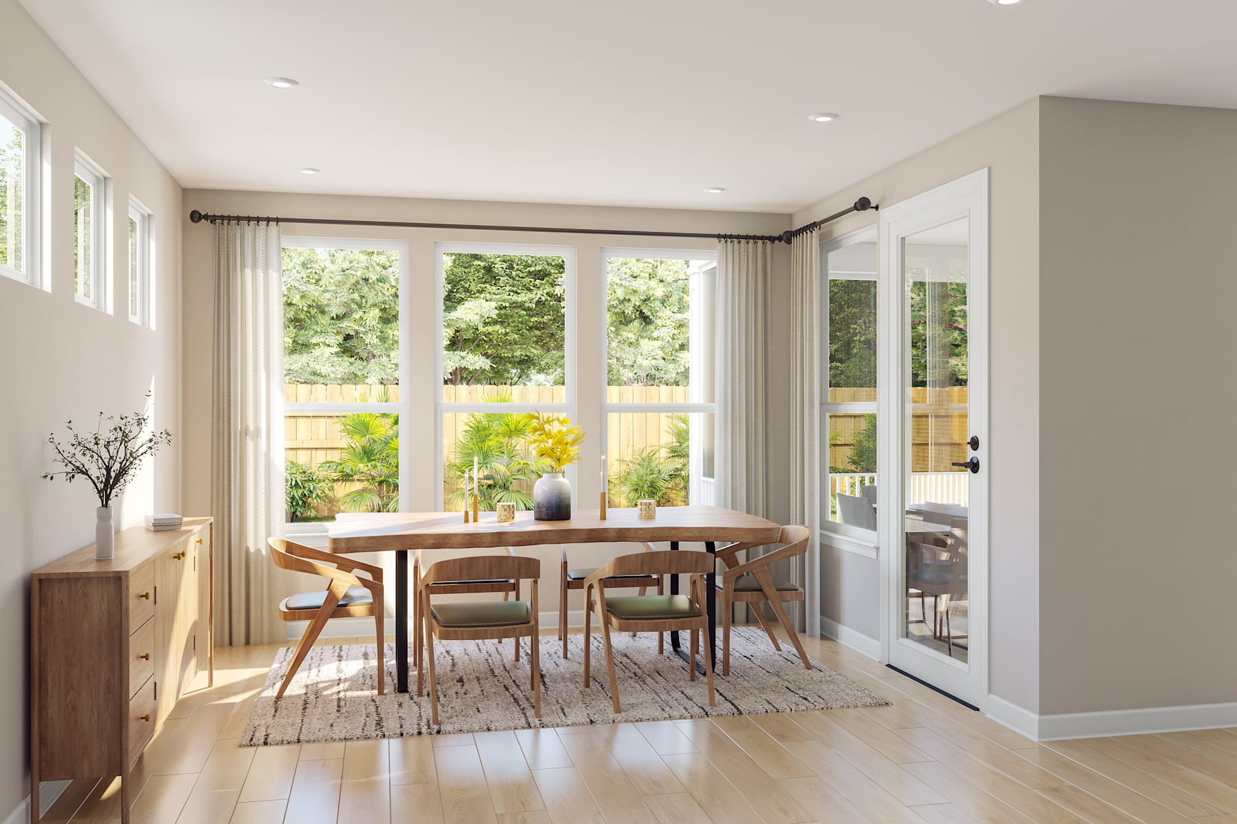 A bright and airy dining room with a wooden table and chairs, surrounded by large windows overlooking a lush outdoor garden.