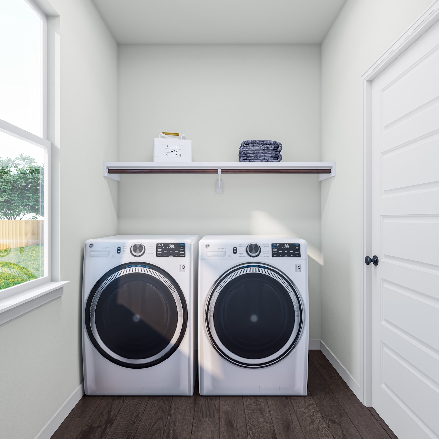 A bright and spacious laundry room with a pair of modern washing machines and a shelf above, holding neatly folded towels.
