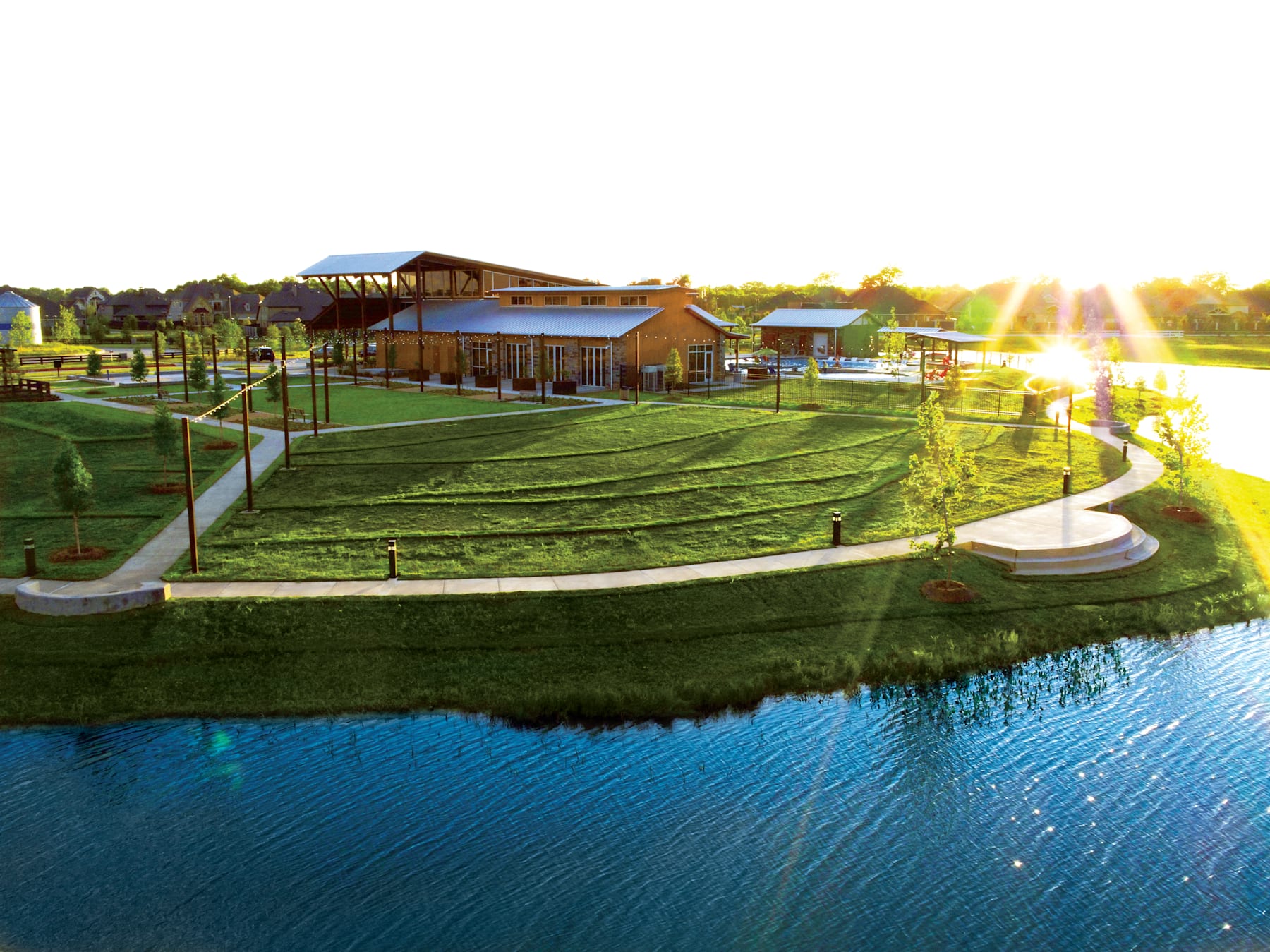 A scenic outdoor area with a large body of water, lush green grass, and a wooden structure with a covered patio overlooking the landscape.