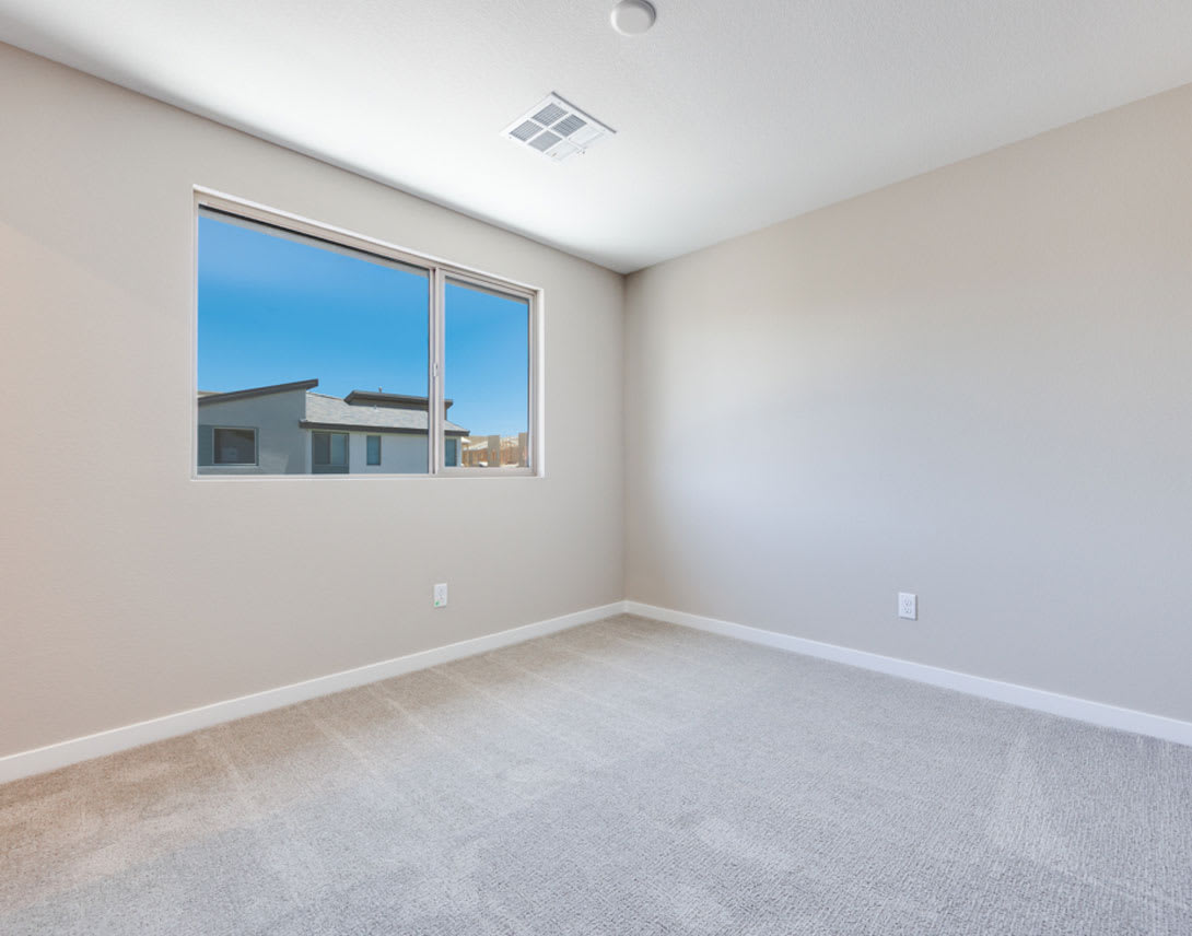 A spacious, well-lit room with a large window overlooking a cityscape, featuring a clean and minimalist interior design.