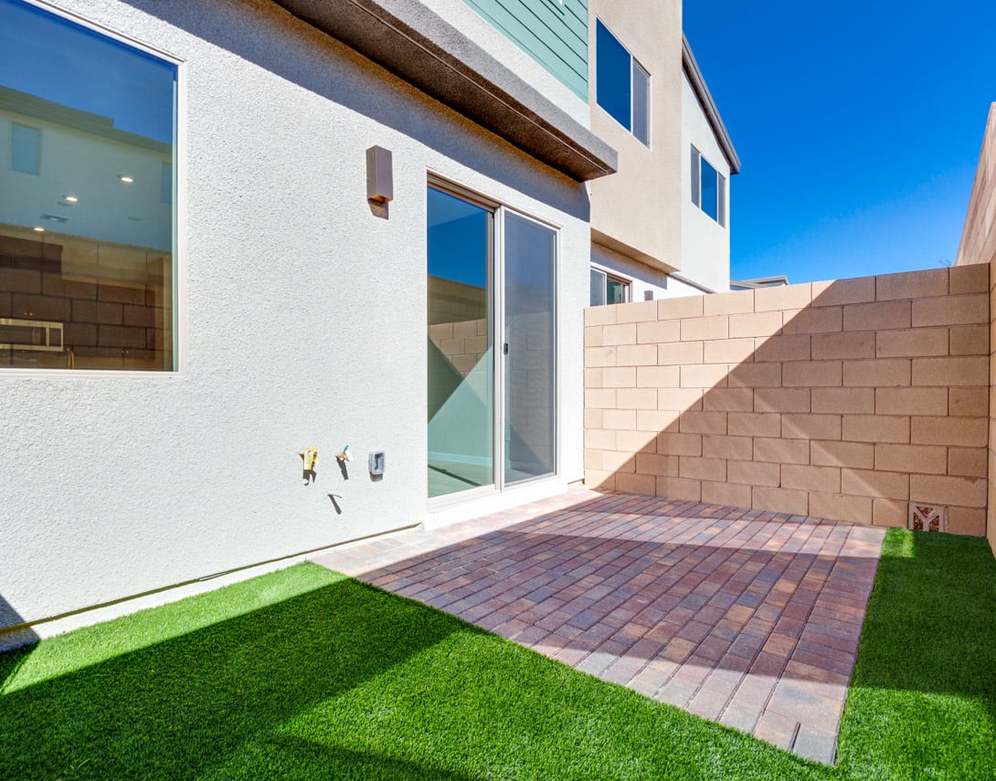 A modern, two-story building with a paved walkway and a well-manicured lawn in the foreground, set against a clear blue sky.